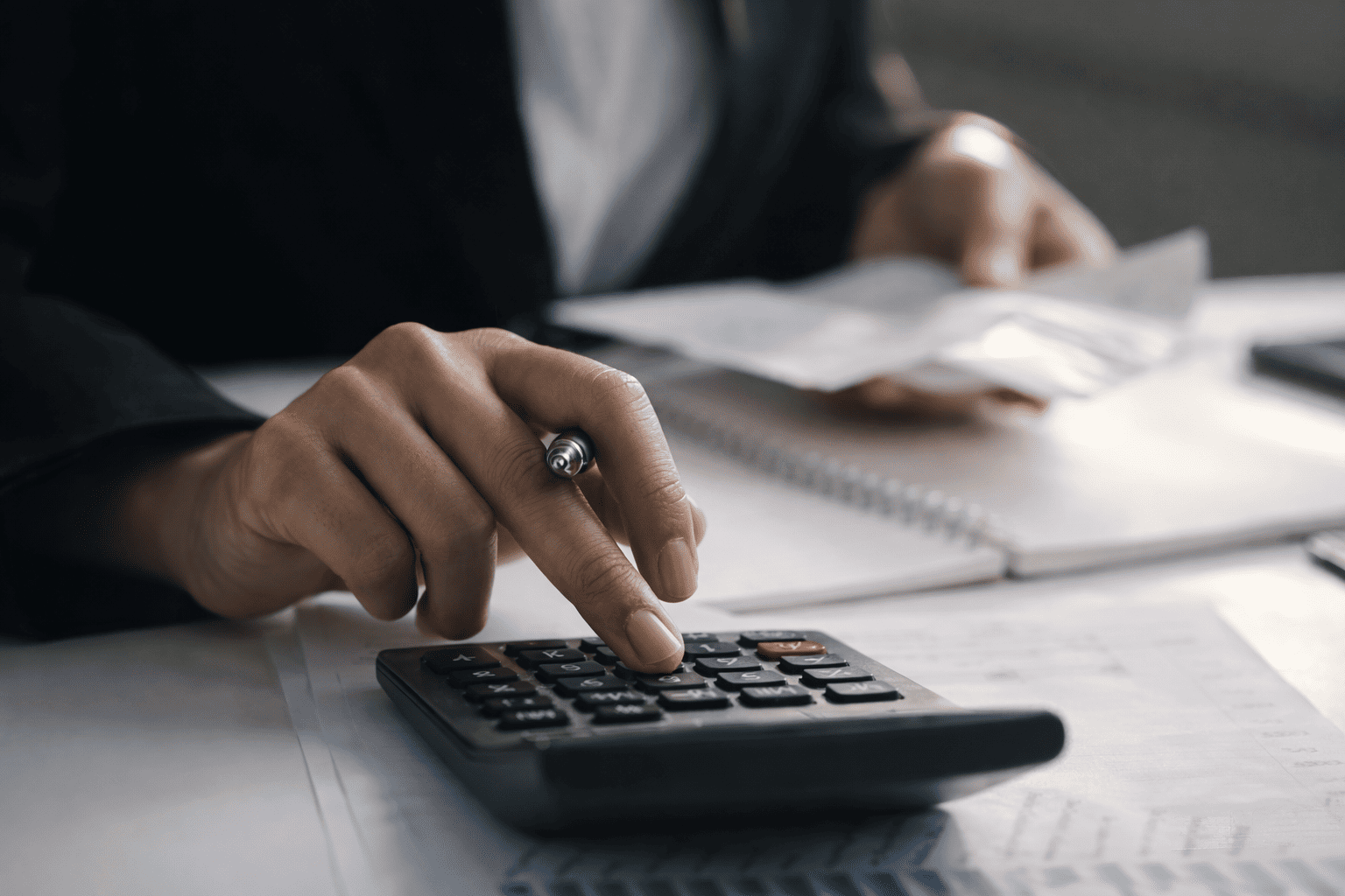 Close-up of a professional using a calculator to review security assessment costs and budget planning documents.