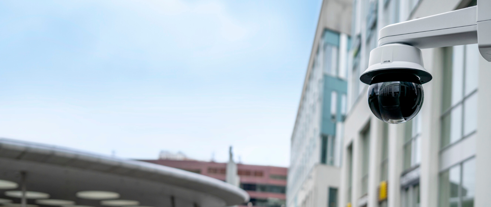 Axis dome security camera installed on a building exterior in an urban environment, providing surveillance coverage for commercial property security in NYC