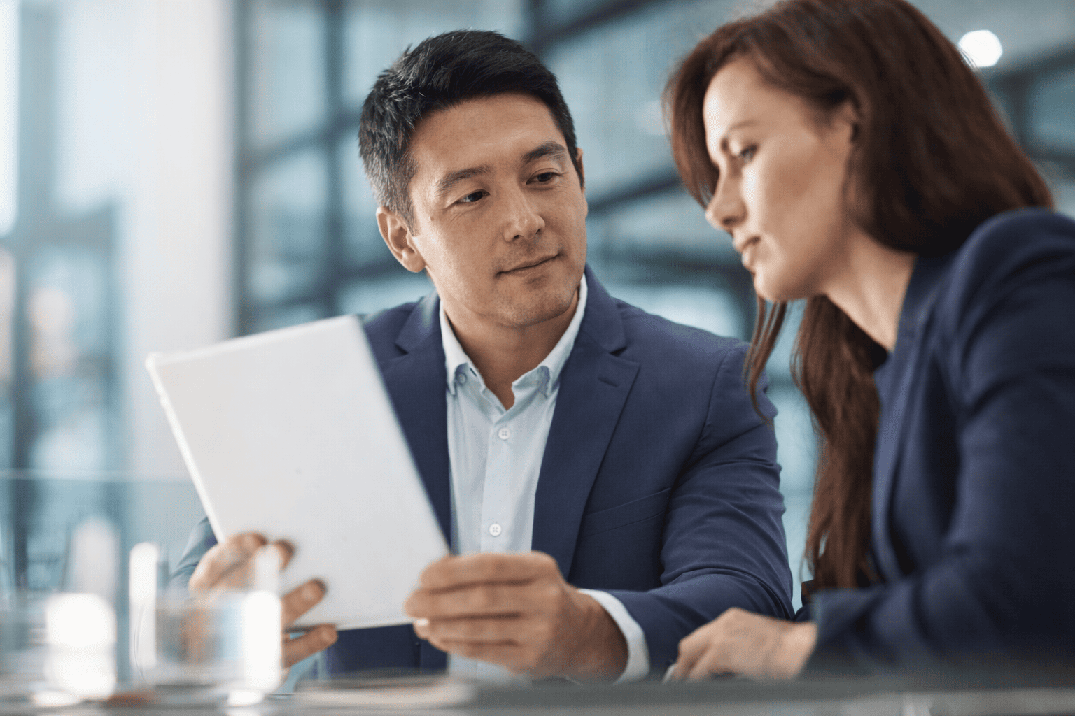 Two business professionals reviewing a tablet during a commercial security consultation meeting in a modern office setting