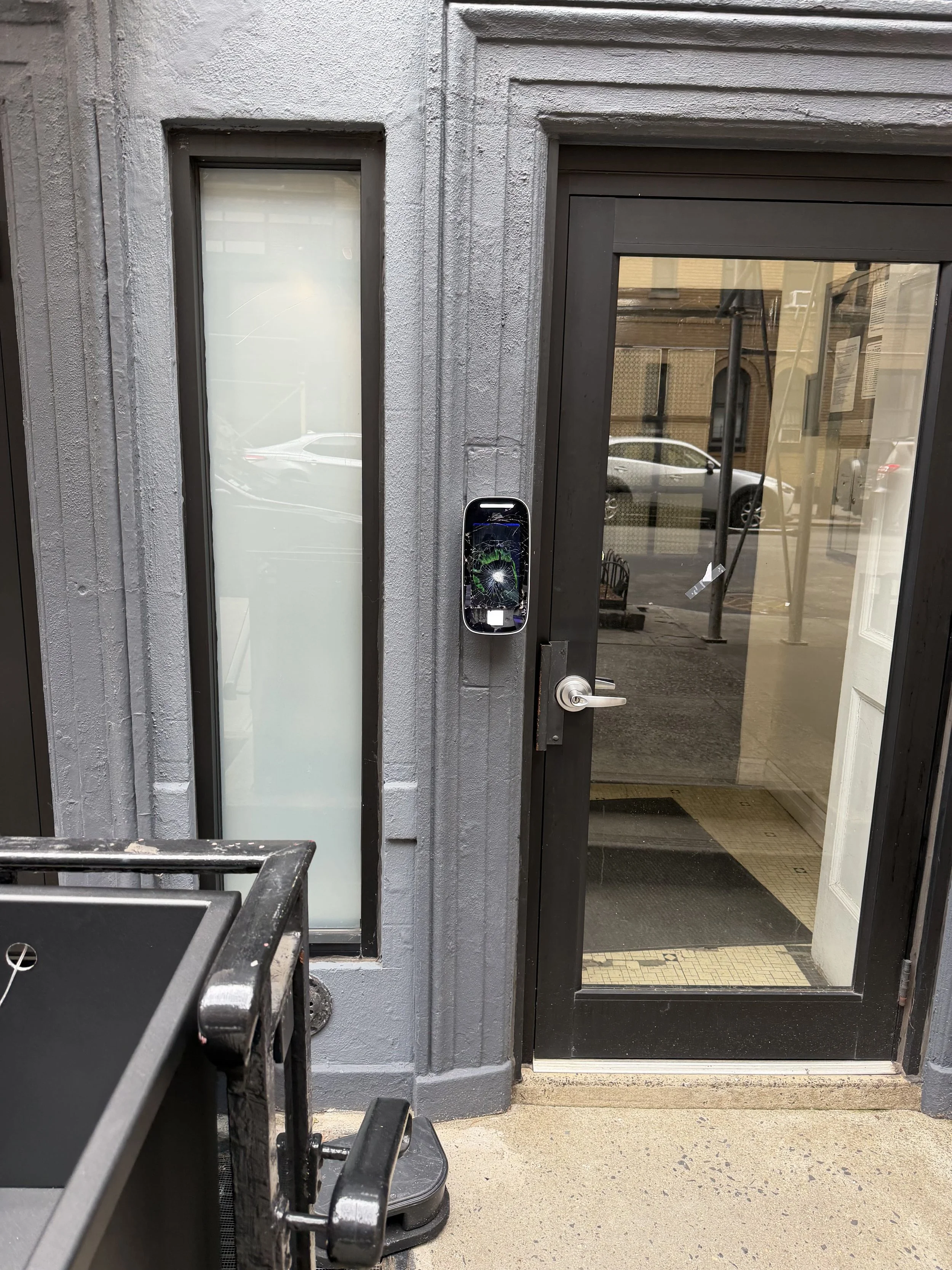 Damaged ButterflyMX intercom system with broken screen at NYC building entrance