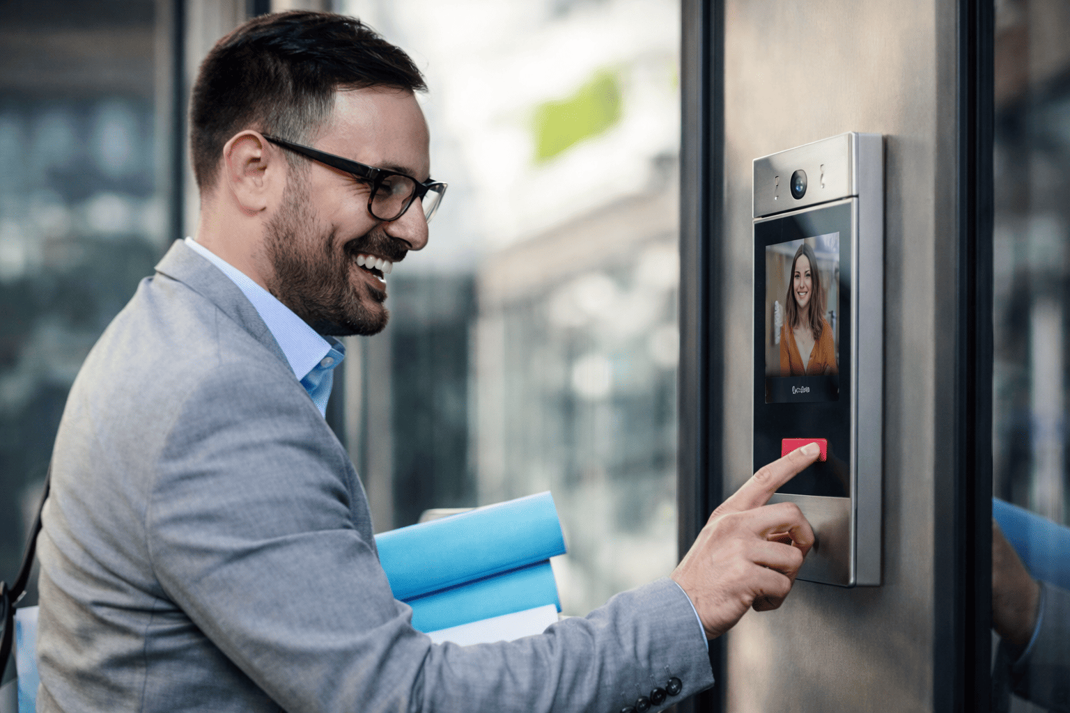 Business professional using a commercial video intercom system at a secured building entrance.