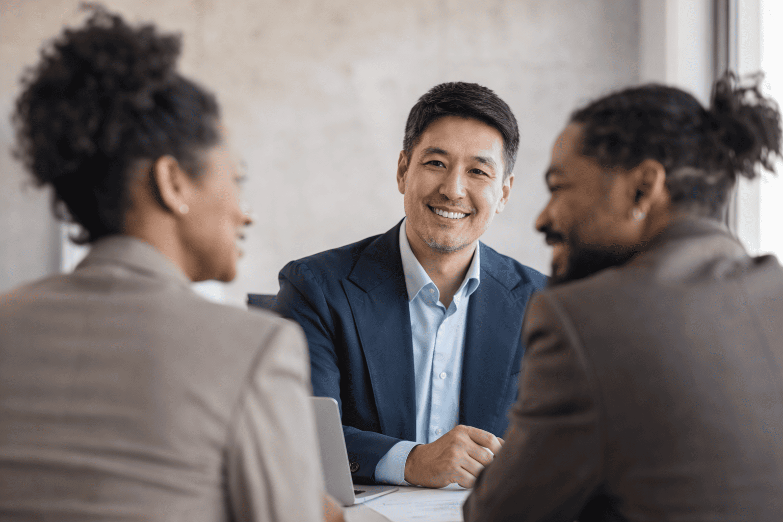 Security consultant smiling while meeting with two clients during a professional business consultation in a modern office.