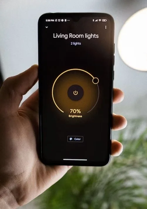 Smartphone controlling Lutron smart lighting system with brightness adjustment and lighting automation through a mobile app.
