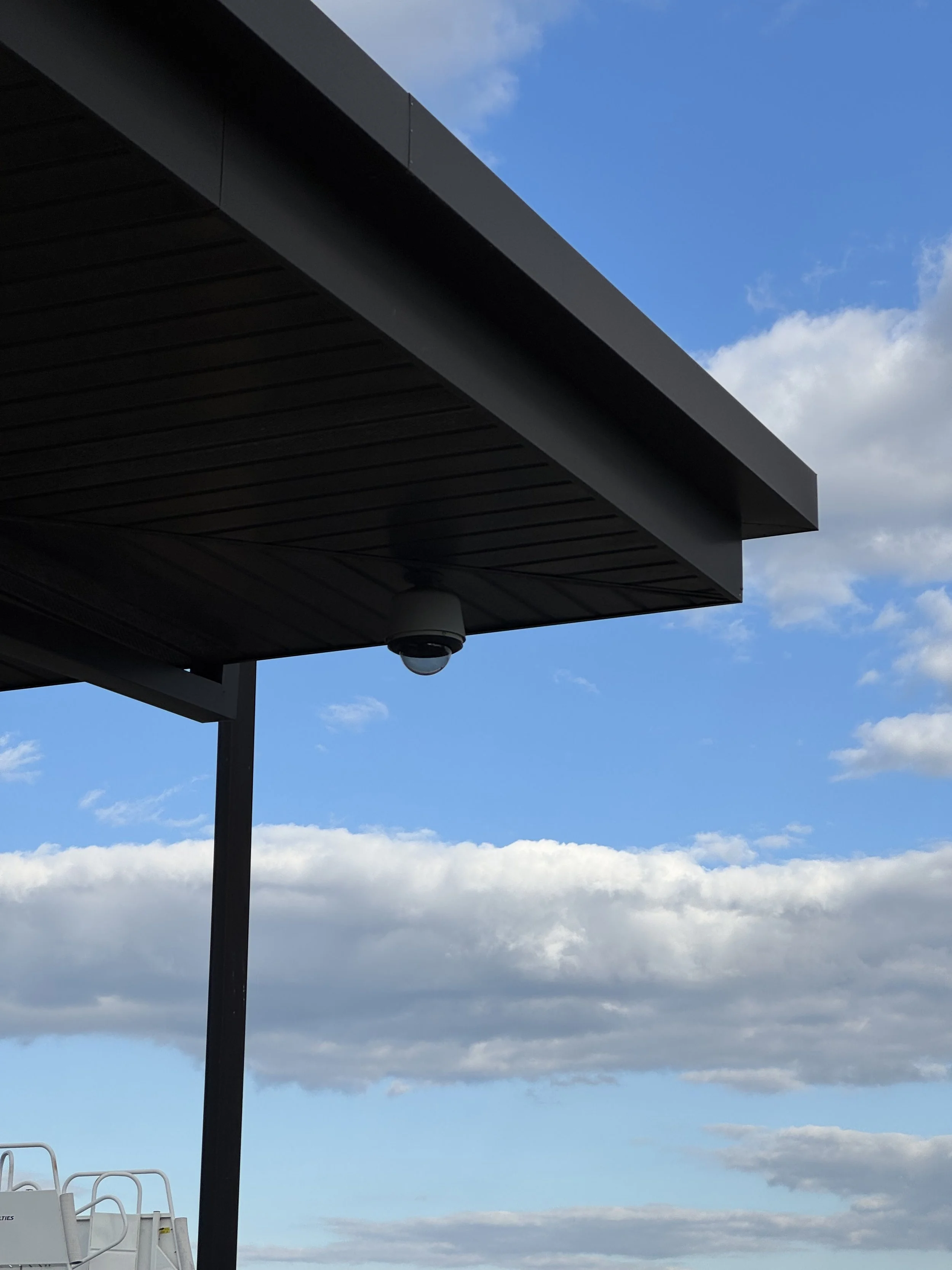 Camera mounted on overhang against blue sky