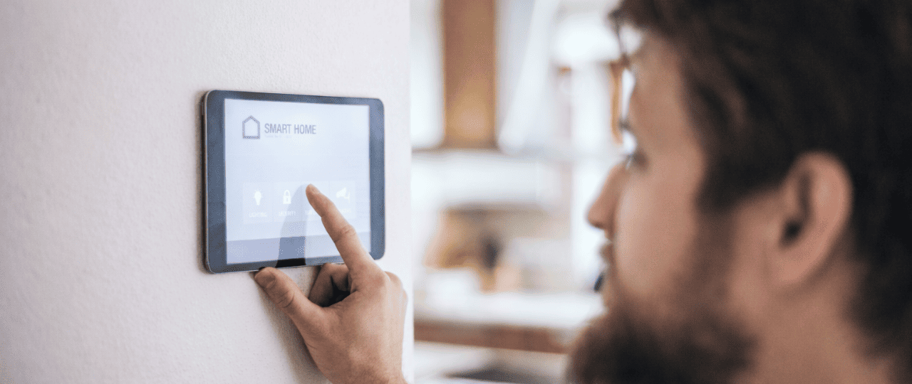 Person using a wall-mounted smart home touchscreen to control residential access and security systems in a modern interior