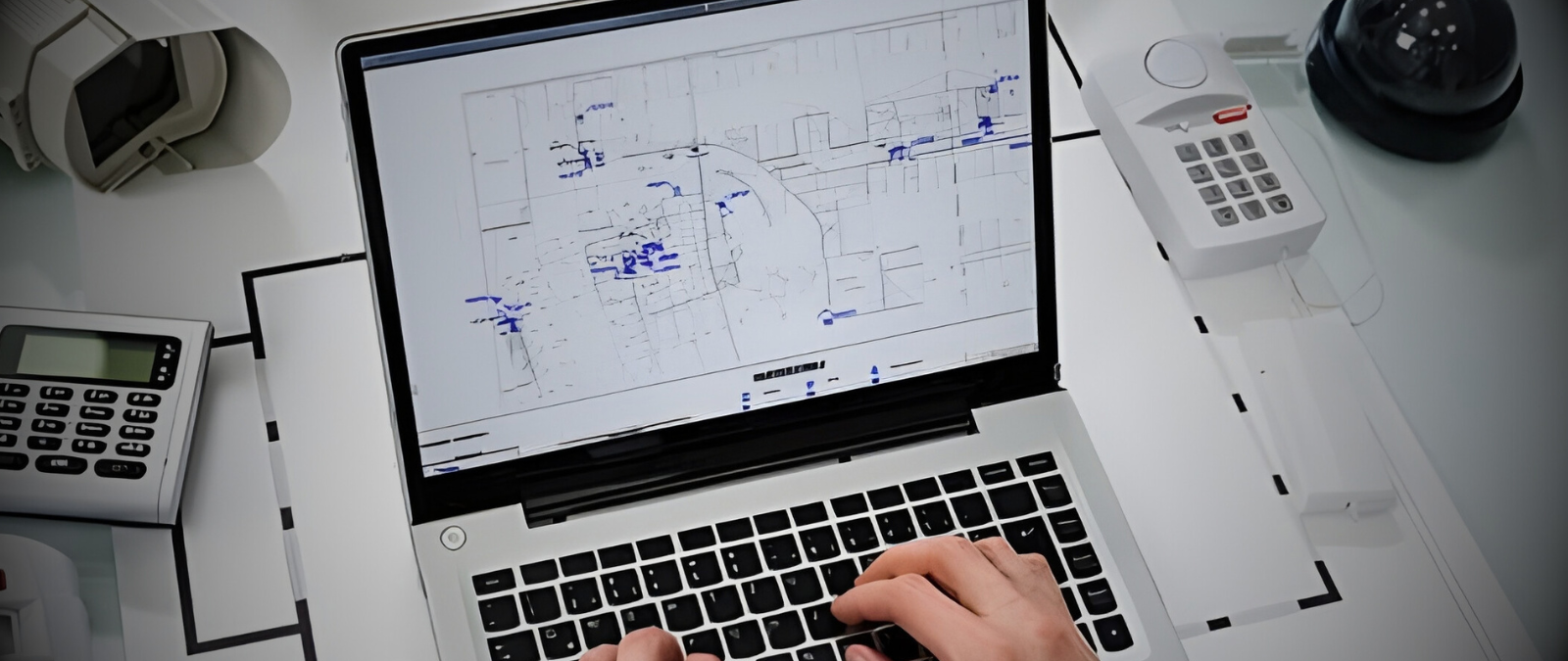 Security professional reviewing a commercial building security system layout and surveillance design on a laptop.