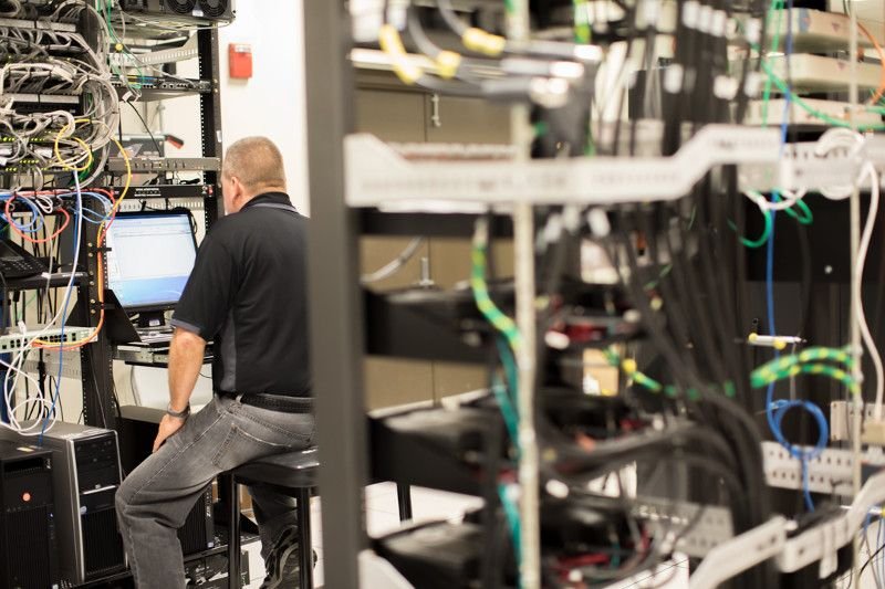Technician working on network servers and security infrastructure as part of a commercial security system modernization project.
