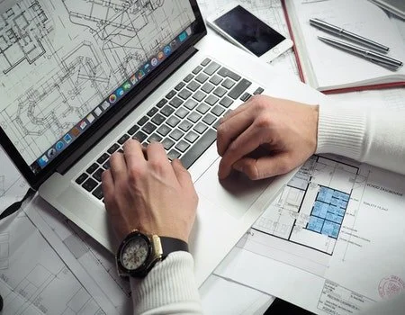 Security professional reviewing system schematics on laptop for proactive issue identification.