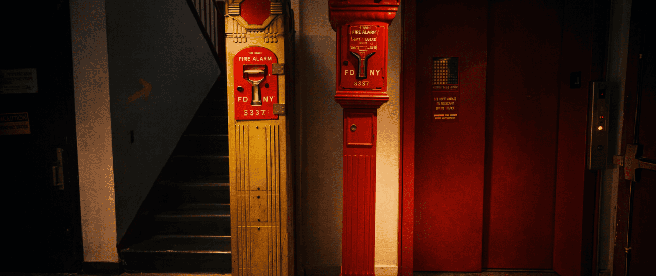 Vintage fire alarm pull stations inside a Manhattan apartment building stairwell in New York City.png