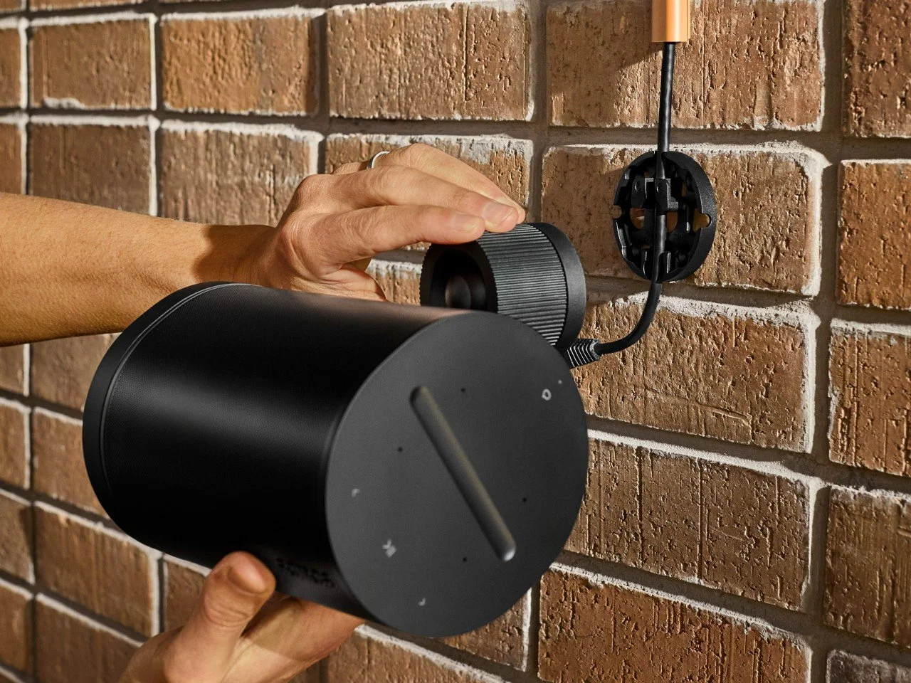Technician installing Sonos speaker on wall with clean cable management in NYC