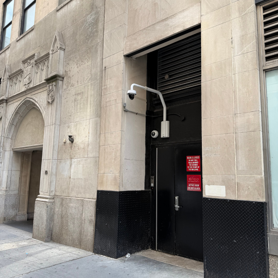 Commercial building exterior with security cameras monitoring a service entrance as part of a professionally planned surveillance system in Manhattan, NYC.