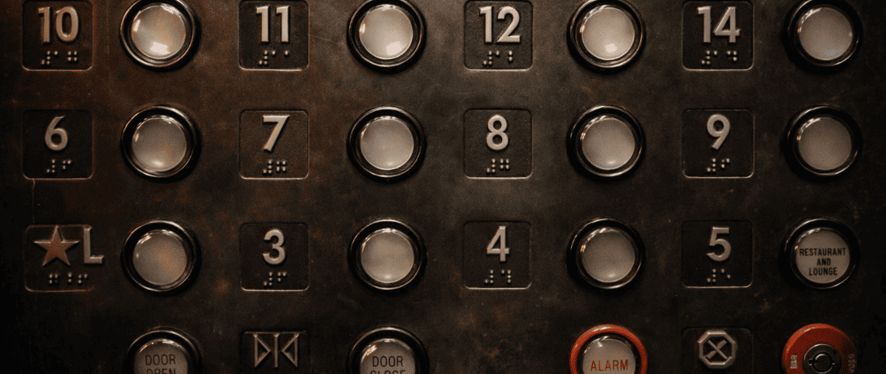 Close-up of an elevator control panel with metallic buttons and braille, highlighting modern building interior design