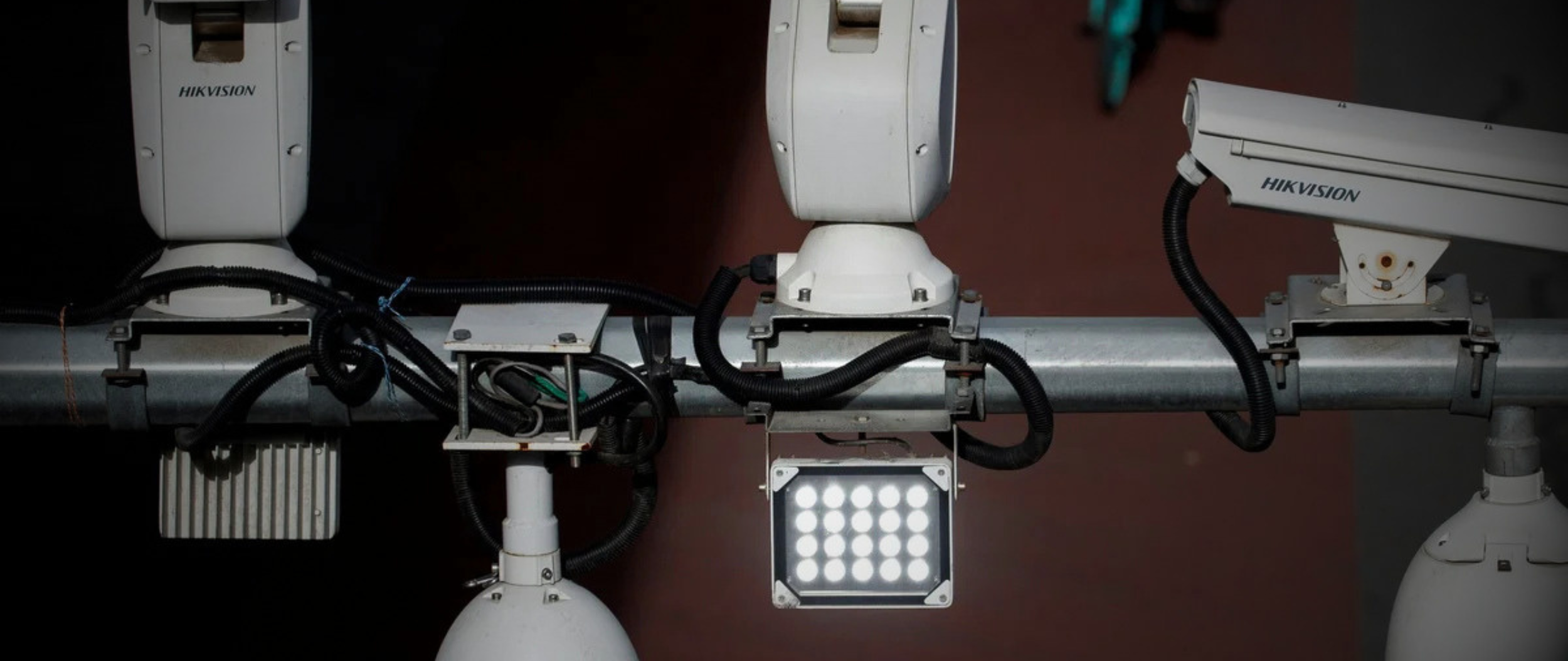 Hikvision surveillance cameras mounted on infrastructure showing real-world installation, highlighting NDAA compliance risks, federal restrictions, and security concerns with non-compliant equipment.
