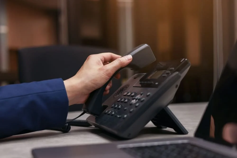 Professional answering a desk phone providing security system support services.