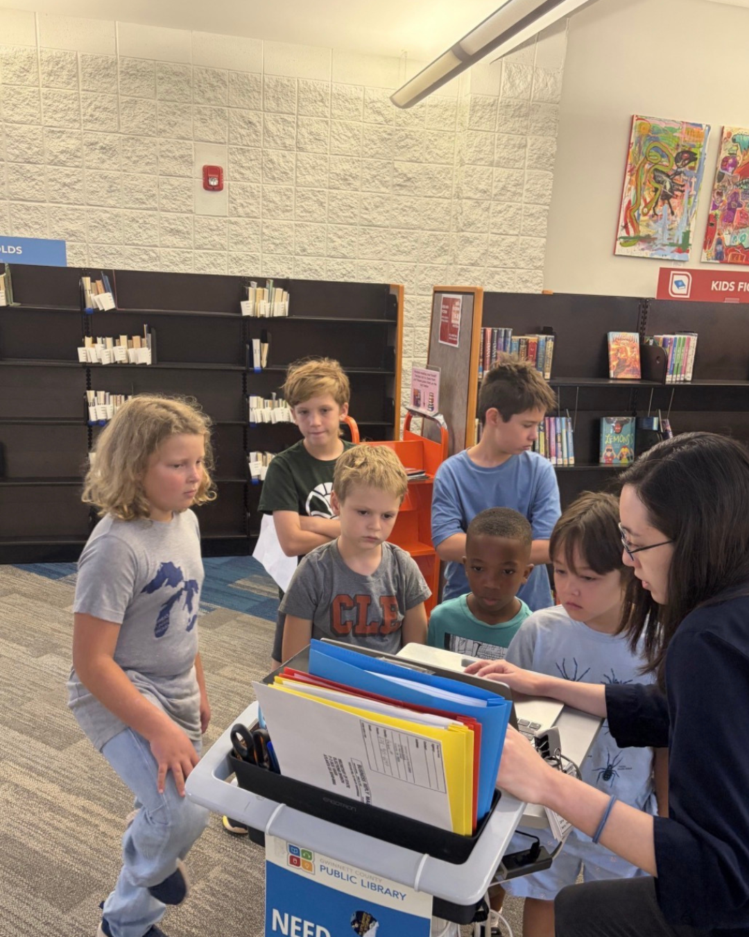 Montessori elementary students on a going out to a Gwinnett Public Library learning from a librarian.