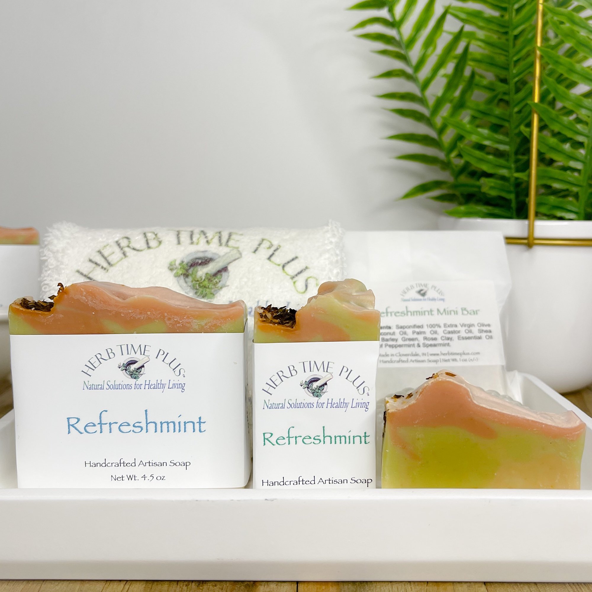 refreshmint-soap-bar.JPEG:three different size bars of refreshmint soap sitting on a tray with a plant and soap bar in the background