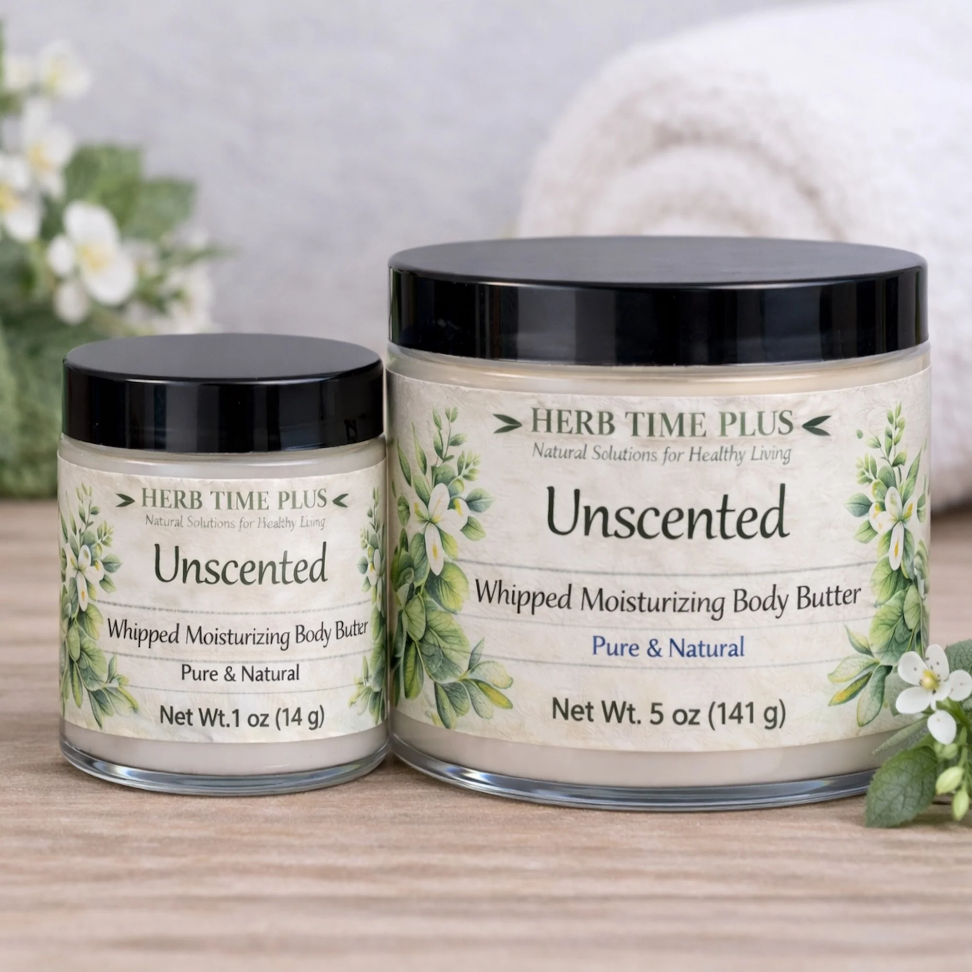 unscented-body-butter.jpg: two jars of unscented body butter 1 oz and 5 oz on a table with a towel behind and a green plant beside them