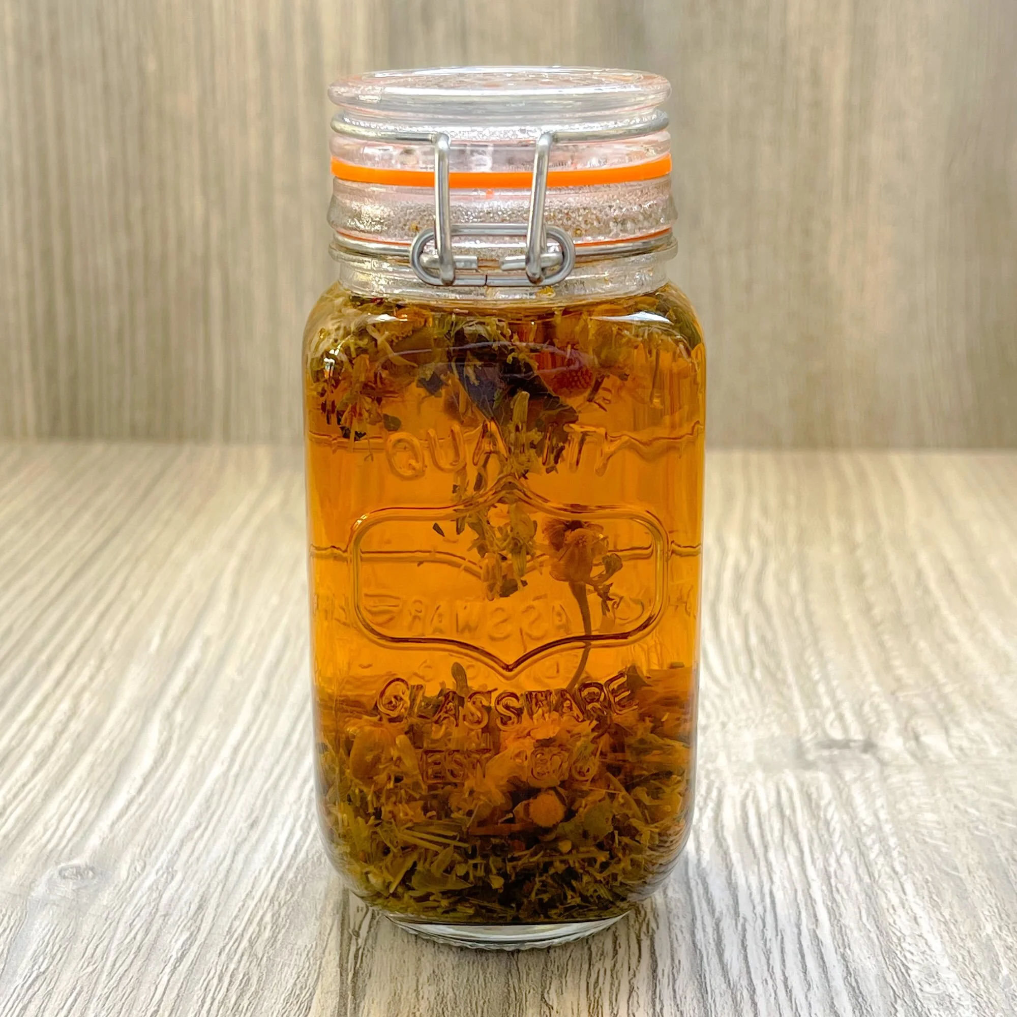 chamomile-comfort-herbal-tea-blend-brewed.jpeg: brewed chamomile comfort herbal tea blend in a glass jar