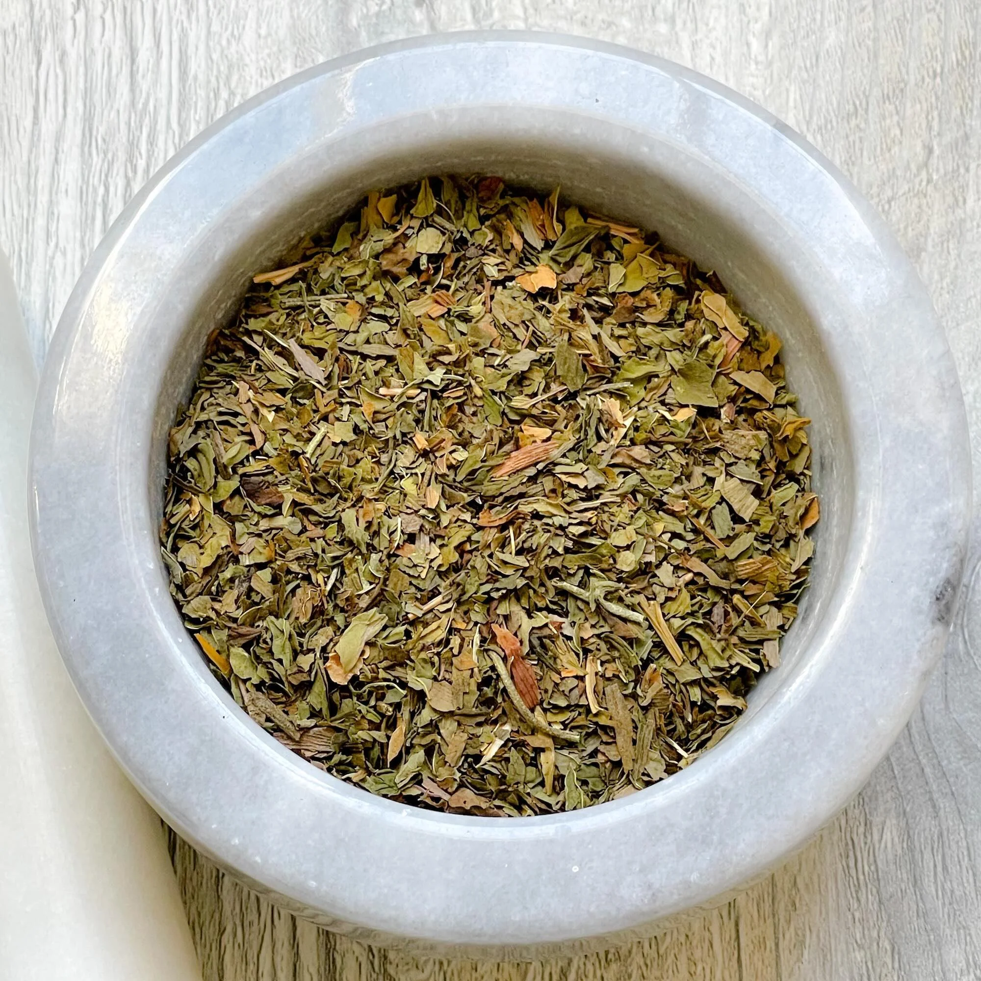 refreshmint-herbal-tea-blend-loose.jpeg: loose refreshmint herbal tea blend in a mortar