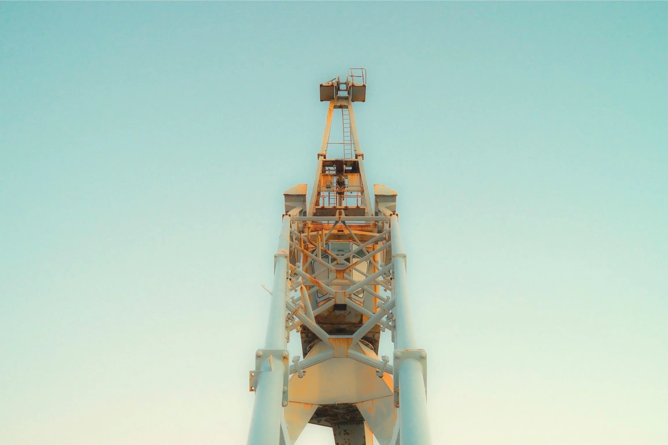 From a low angle, a tall communication tower extends upward into a clear blue sky.