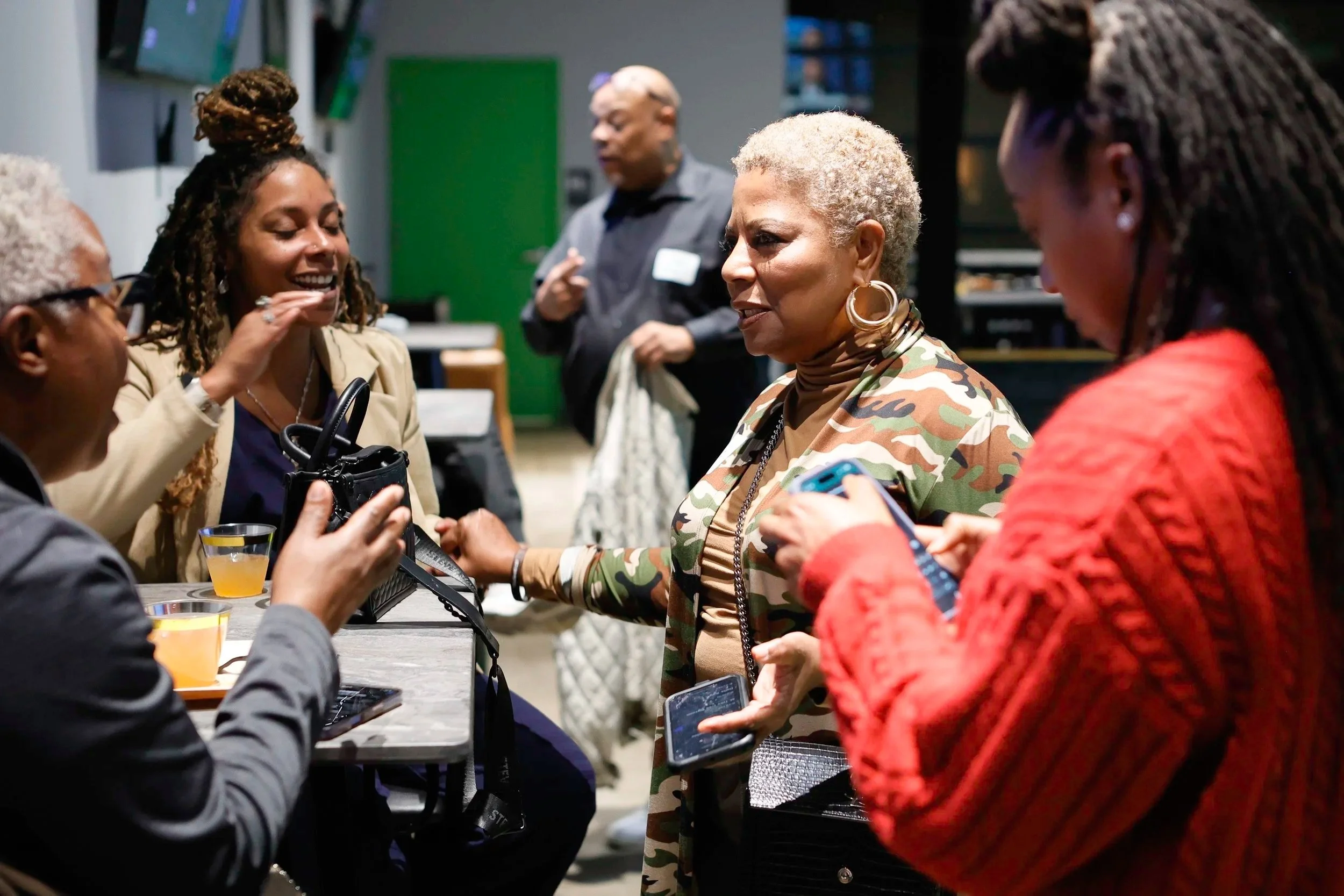 Women and men engaging in conversation at a social gathering, with drinks on the table.