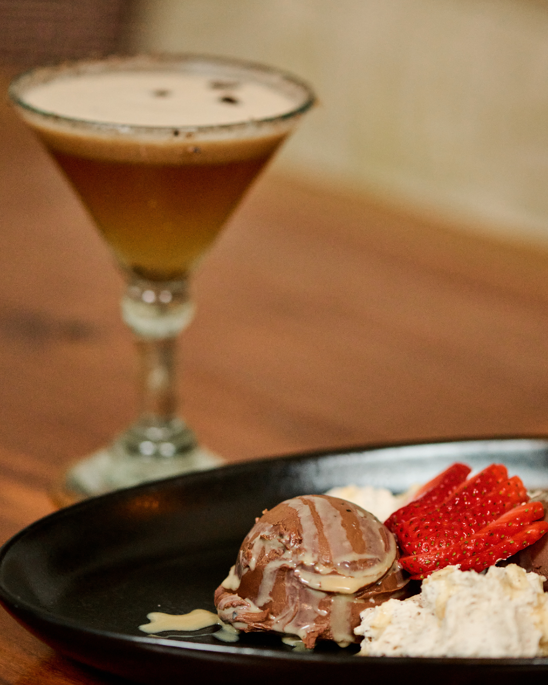 Tropic Java craft cocktail featuring NC Cap & Cane Coffee Rum, Frangelico, house-made cinnamon vanilla simple syrup, &  coconut cream. Served up
with a Sea Love Cinnamon Salt rim. Garnished with coffee beans served alongside an elegant black plate of