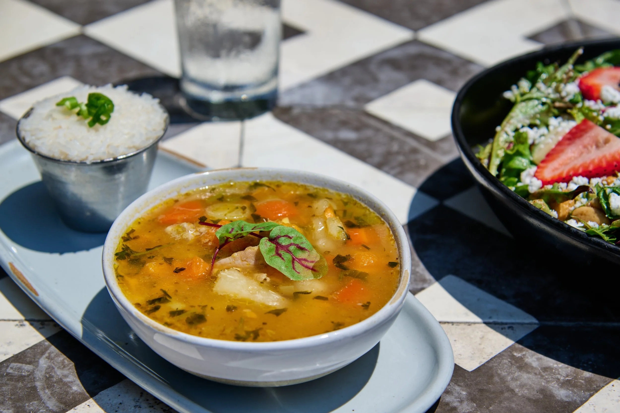 
Bowl of Sancocho,
Panama’s national soup dish & the best cure for a hangover! chicken, sweet potatoes, yucca, plantains & corn in a cilantro broth, served with a side of coconut rice, freshly filtered water and strawberry arugula salad on the side.
