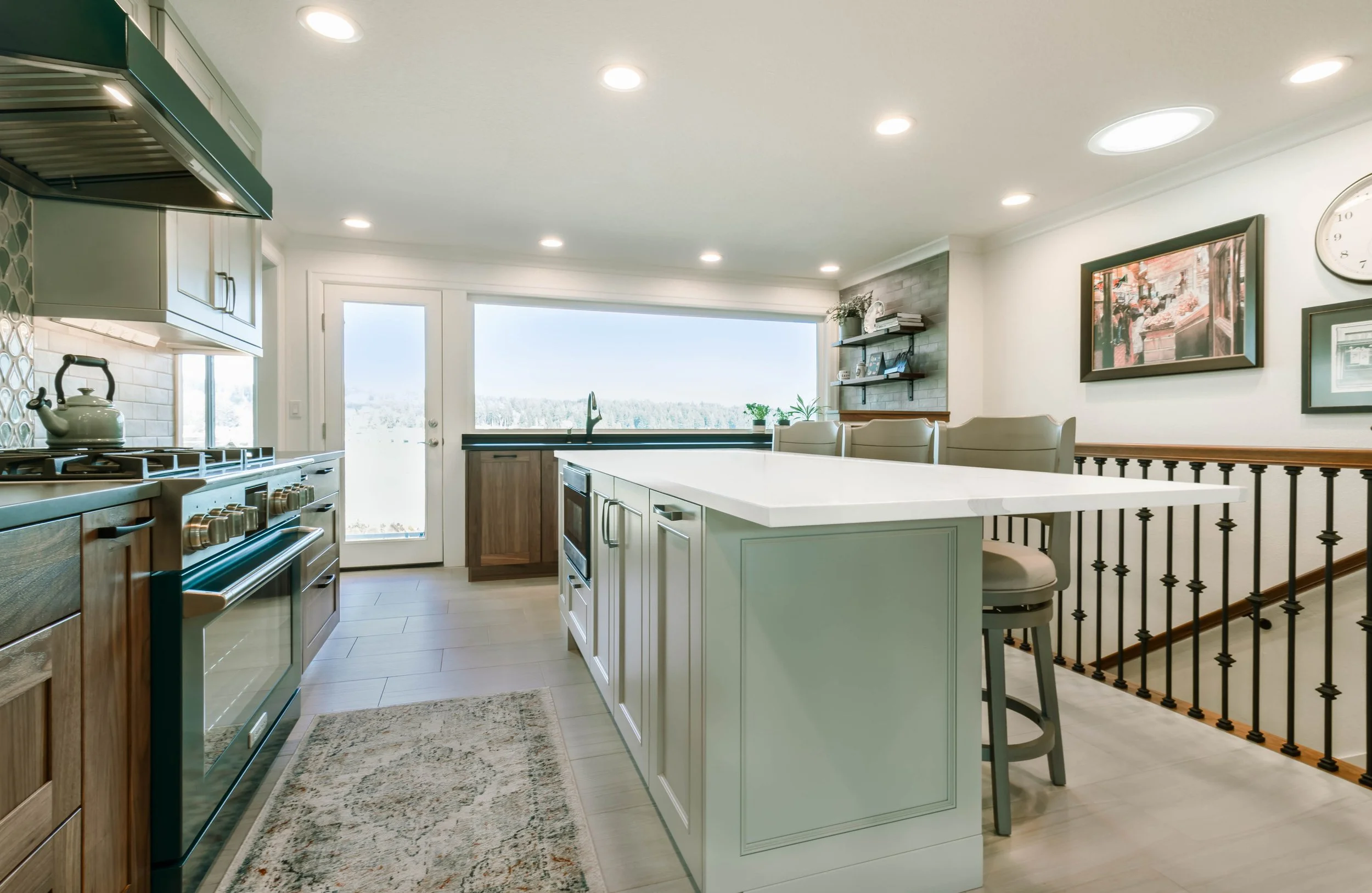 Bright kitchen with white island, wooden cabinets, and large window with outdoor view.