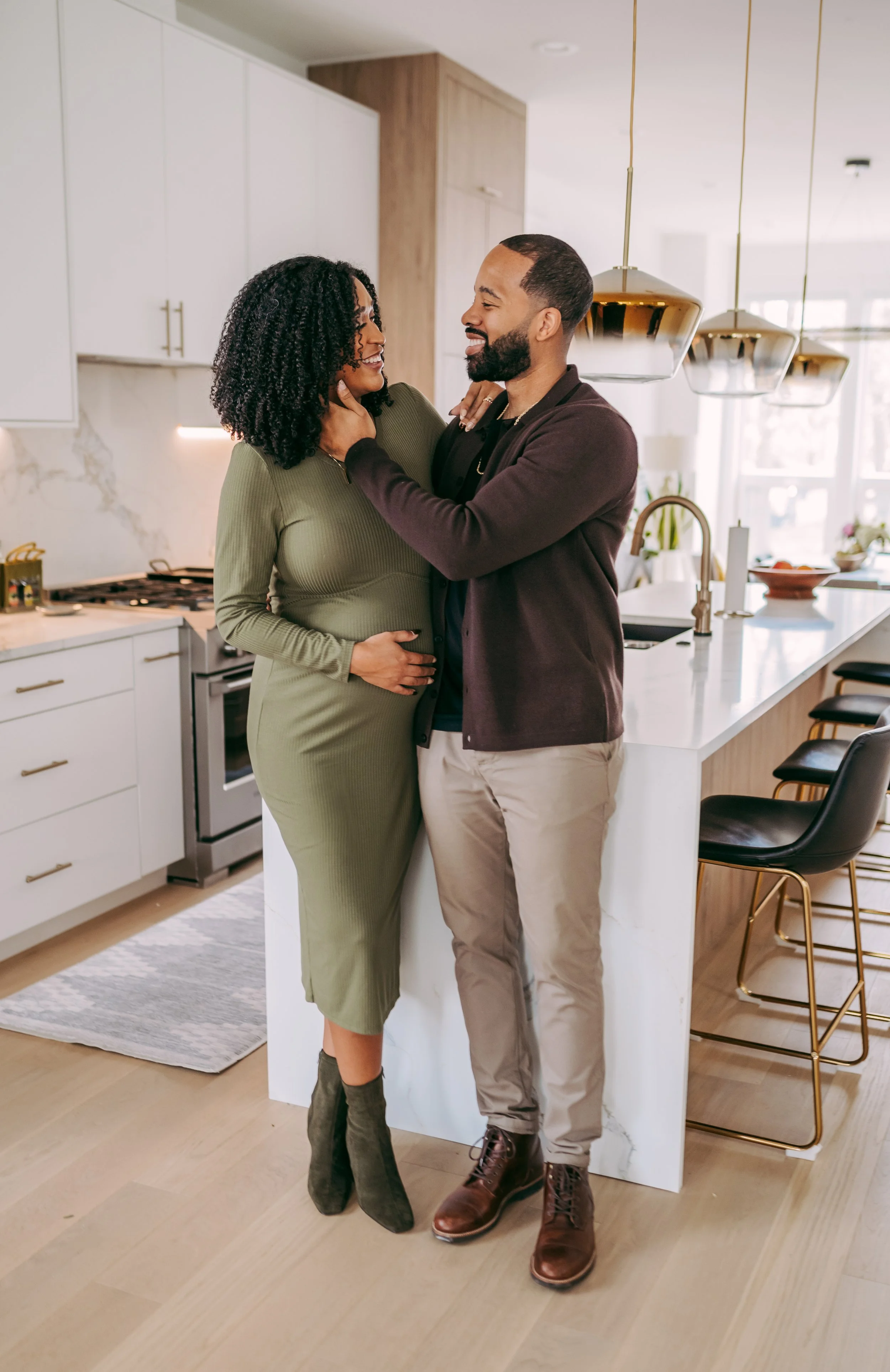 A smiling couple embracing each other happily in a modern kitchen.