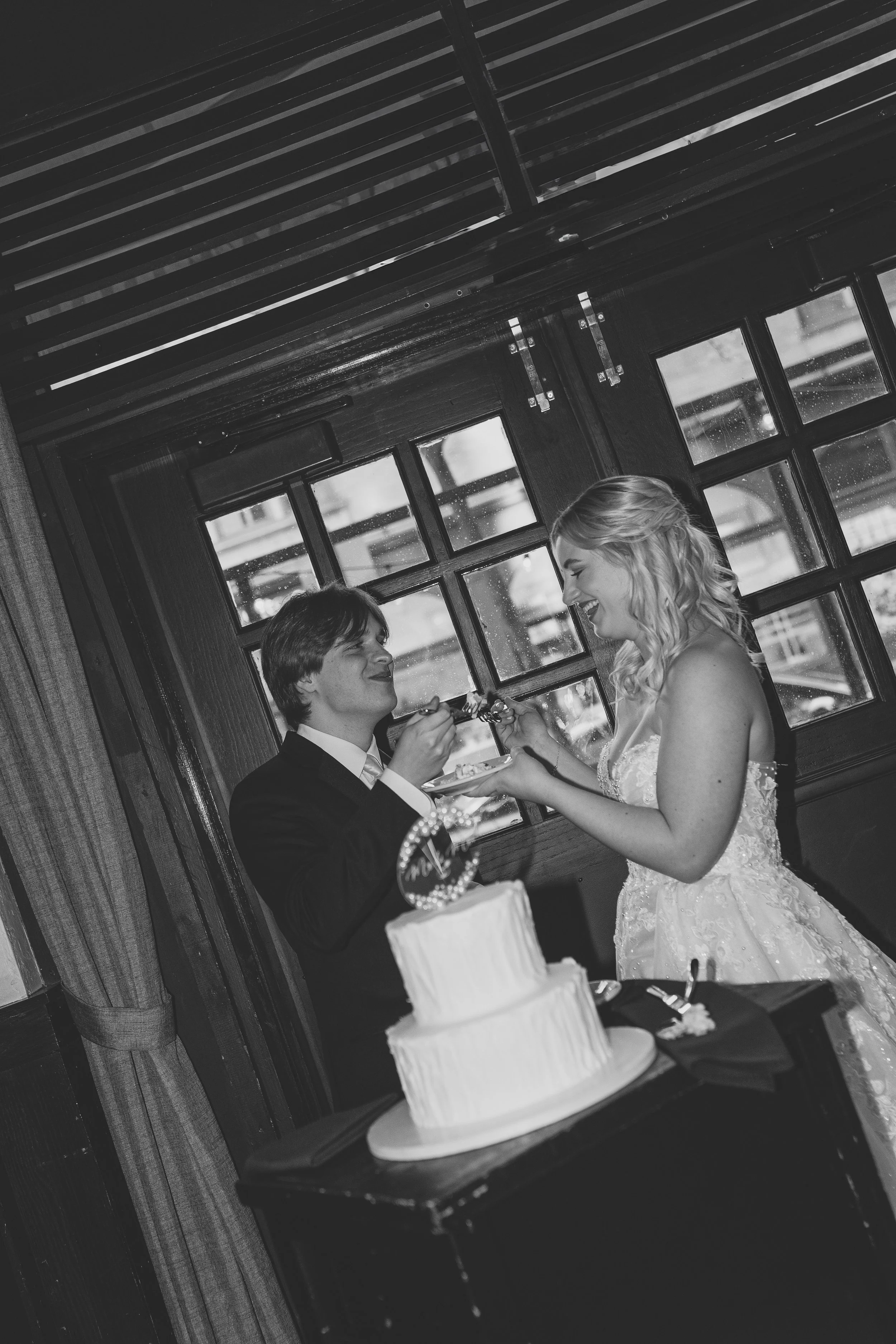 A bride and groom sharing a special moment at their wedding reception, with a wedding cake in the foreground.