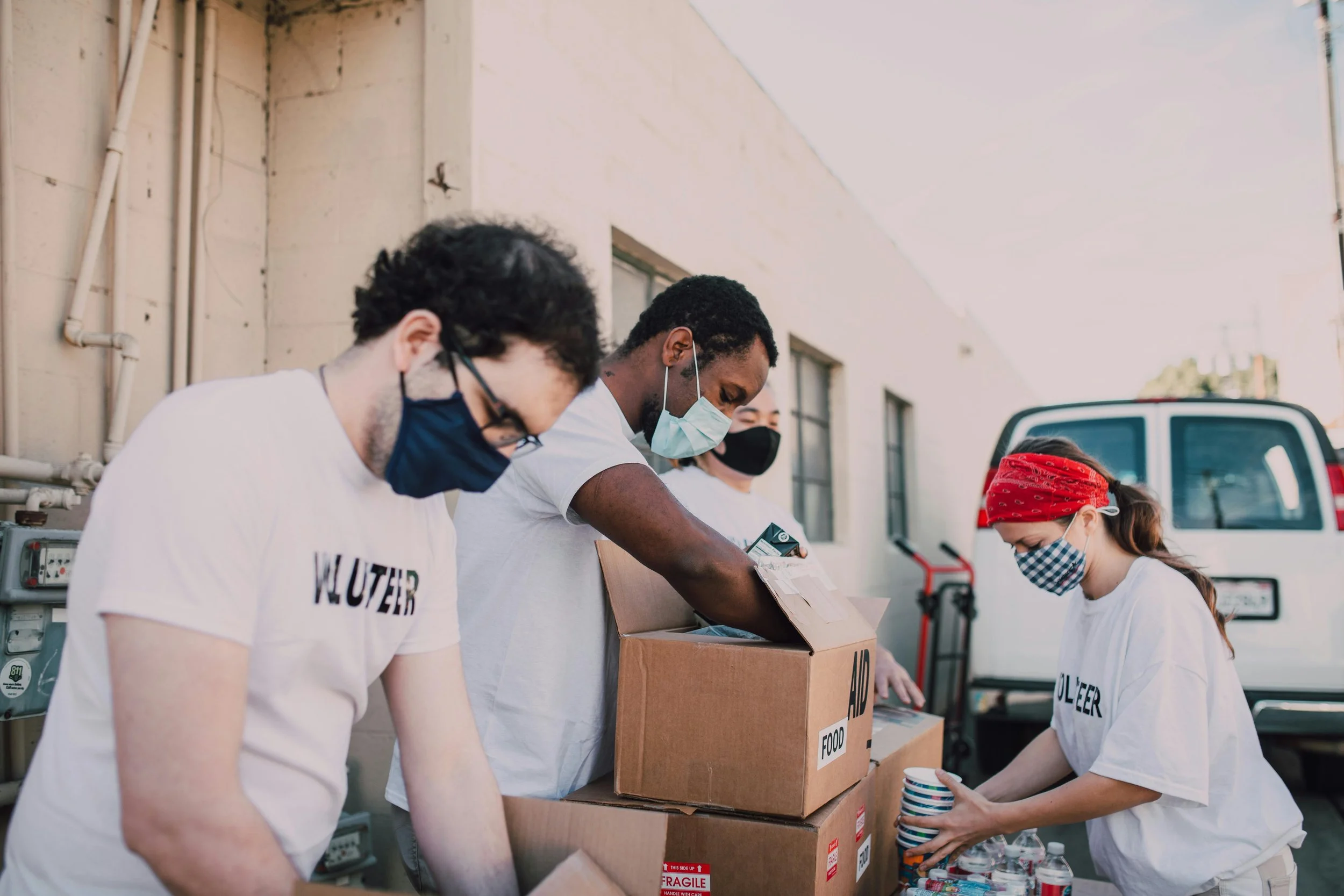 People wearing masks packing food and supplies into boxes for a community service or food drive.