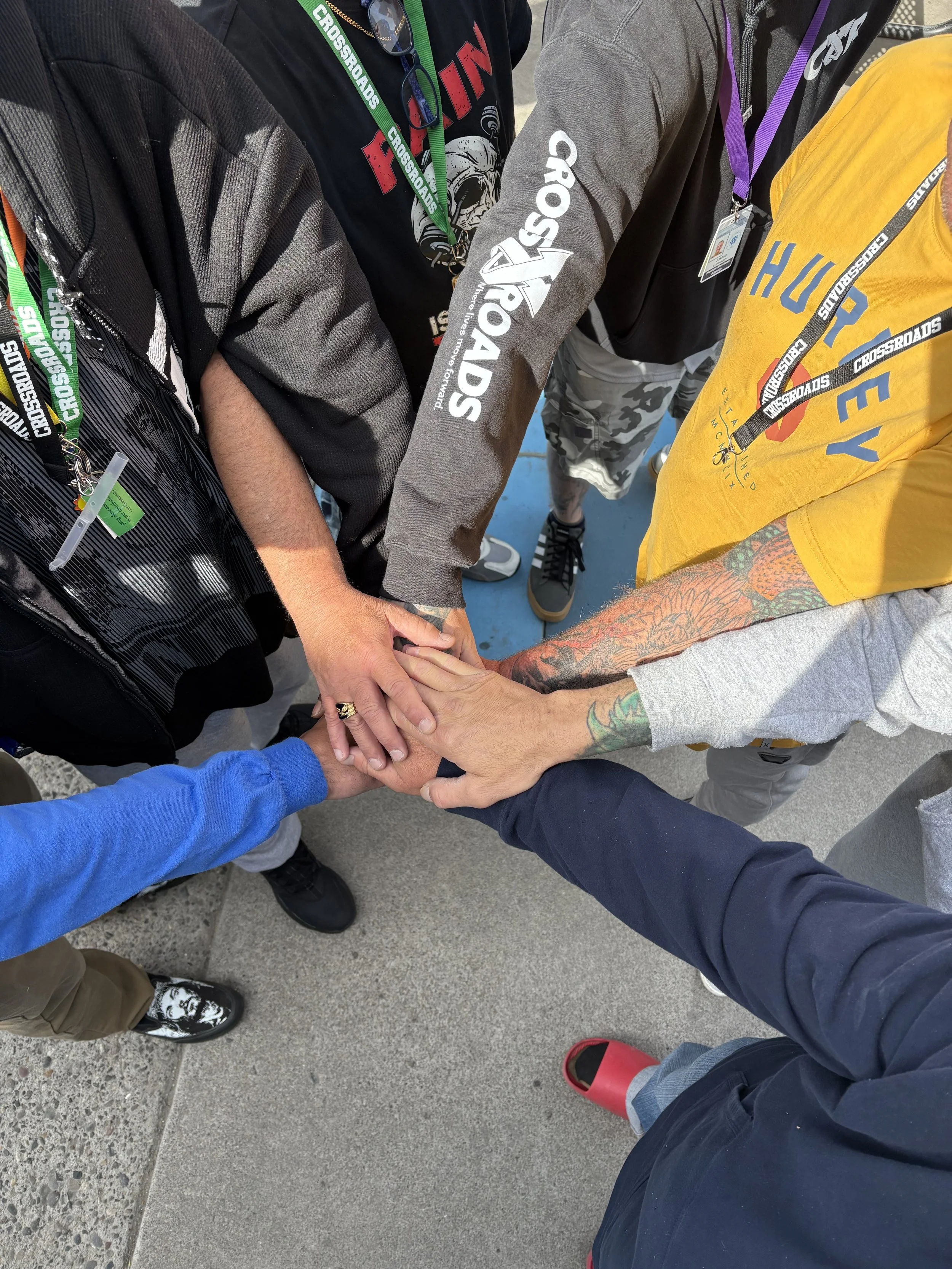 A group of people huddled together with their hands stacked in the center, symbolizing teamwork or unity.