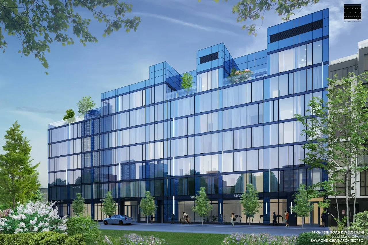 Modern glass building with reflective windows, green landscaping including trees and shrubs, people walking on the sidewalk, and a car parked in front.