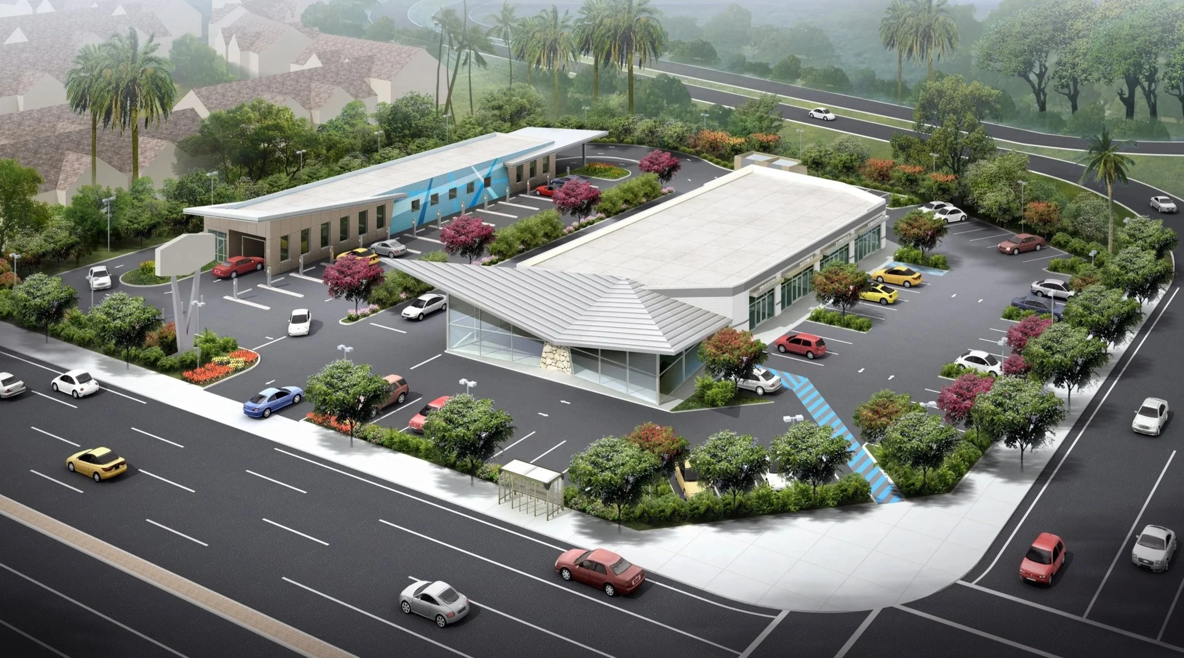 A large commercial building with parking lots, surrounded by trees and greenery, at the corner of a busy multi-lane road.