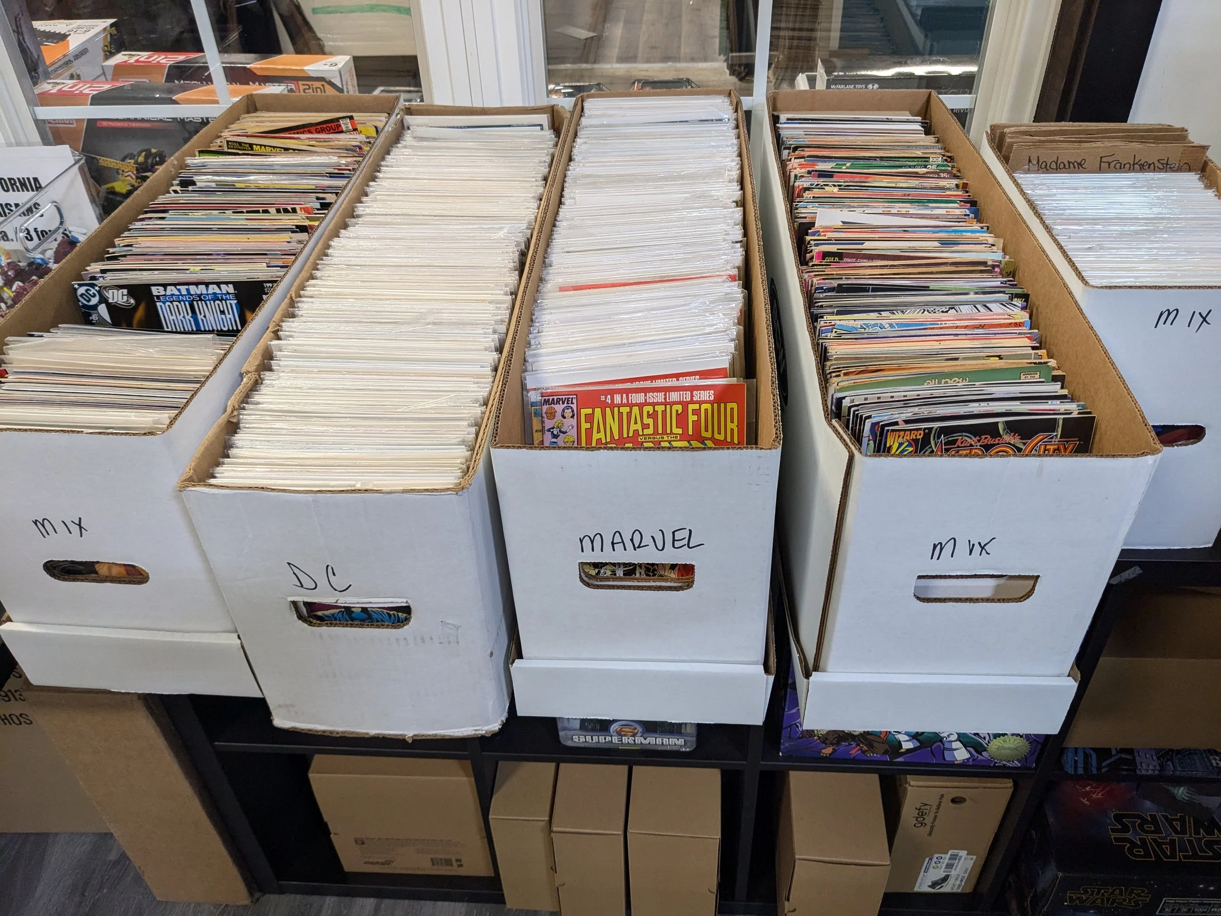 Long boxes filled with comic books, labeled 'MIX', 'DC', 'MARVEL', and 'MIX',