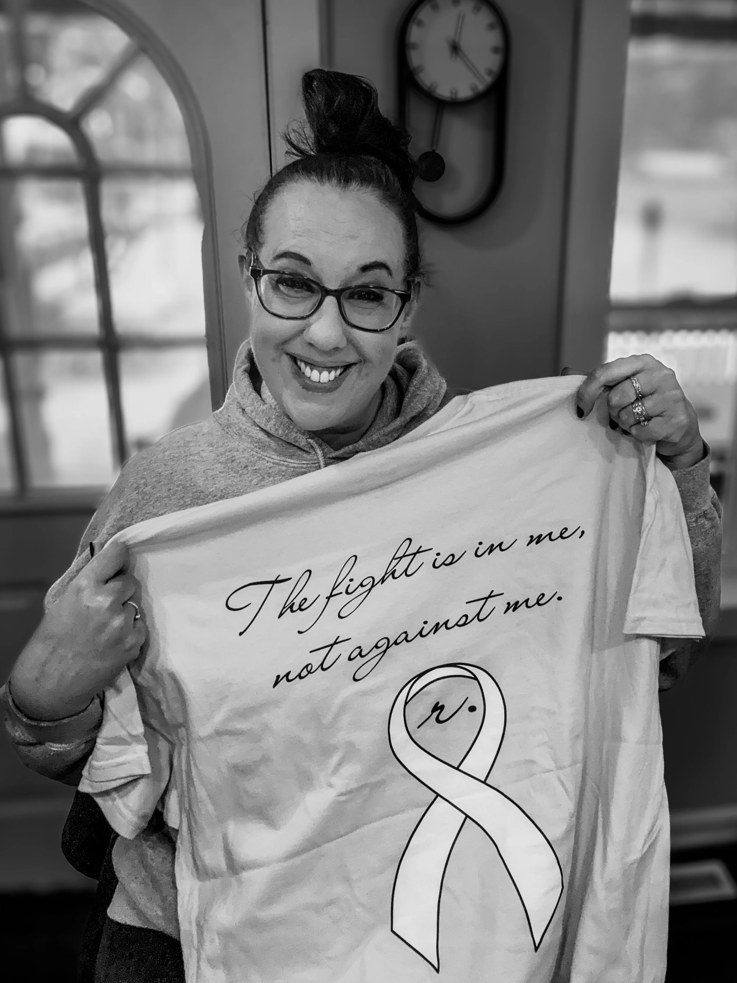 Founder, Kim Survil holding up the back of a FIGHTER. shirt to support children fighting cancer.