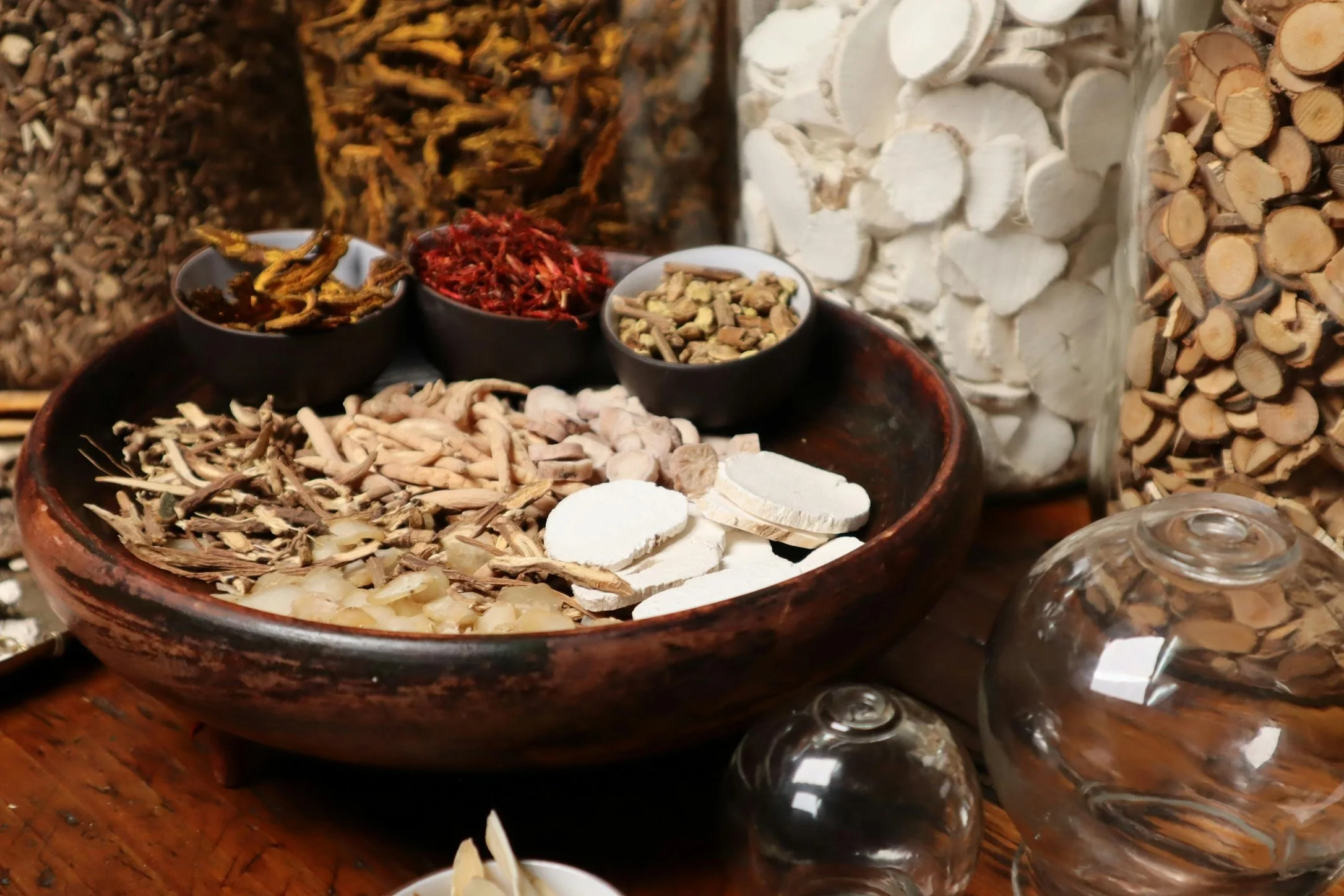 A variety of Chinese herbs stored in glass jars and containers.