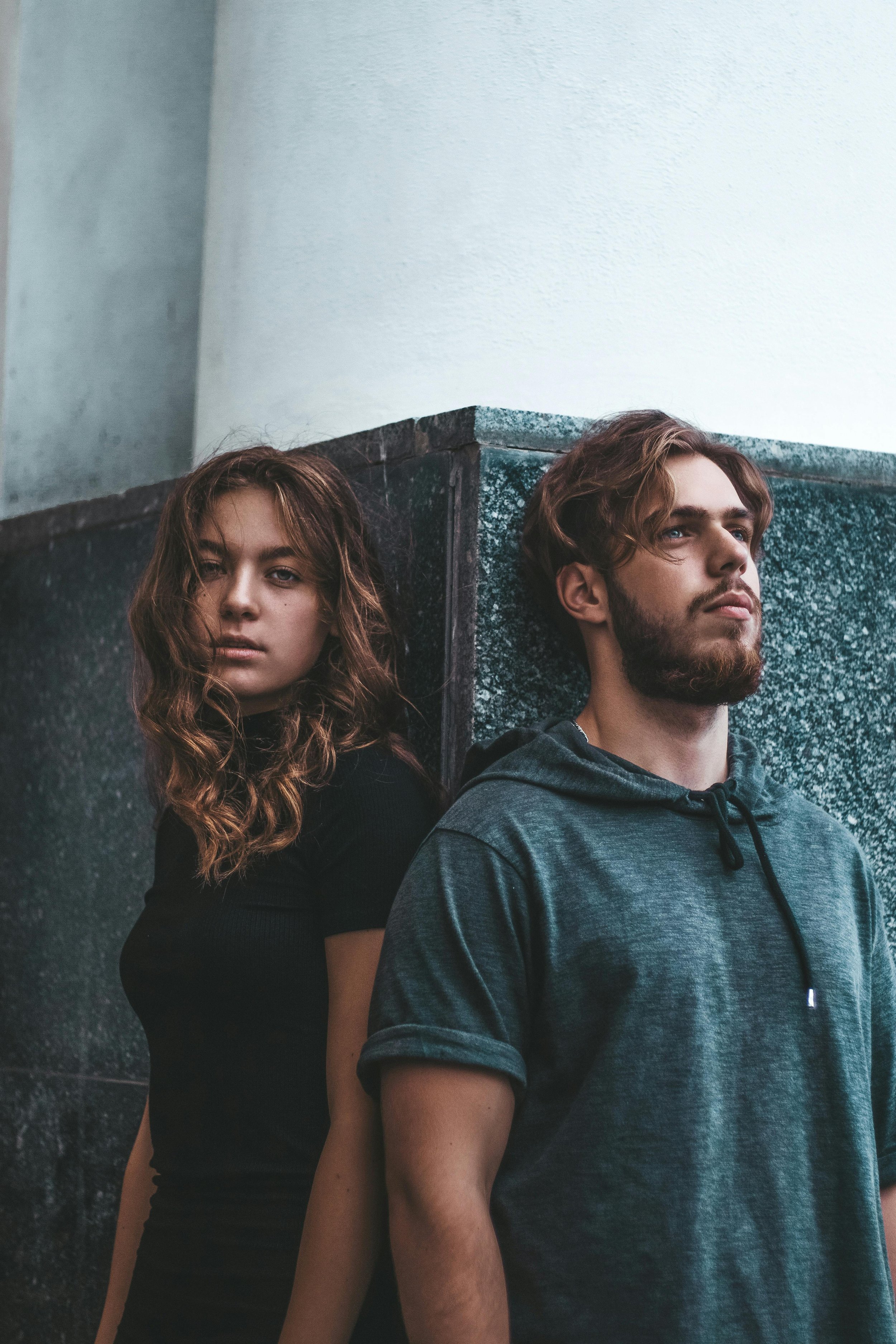 White woman looking into camera, standing perpendicular to a man who is look away from the camera. 