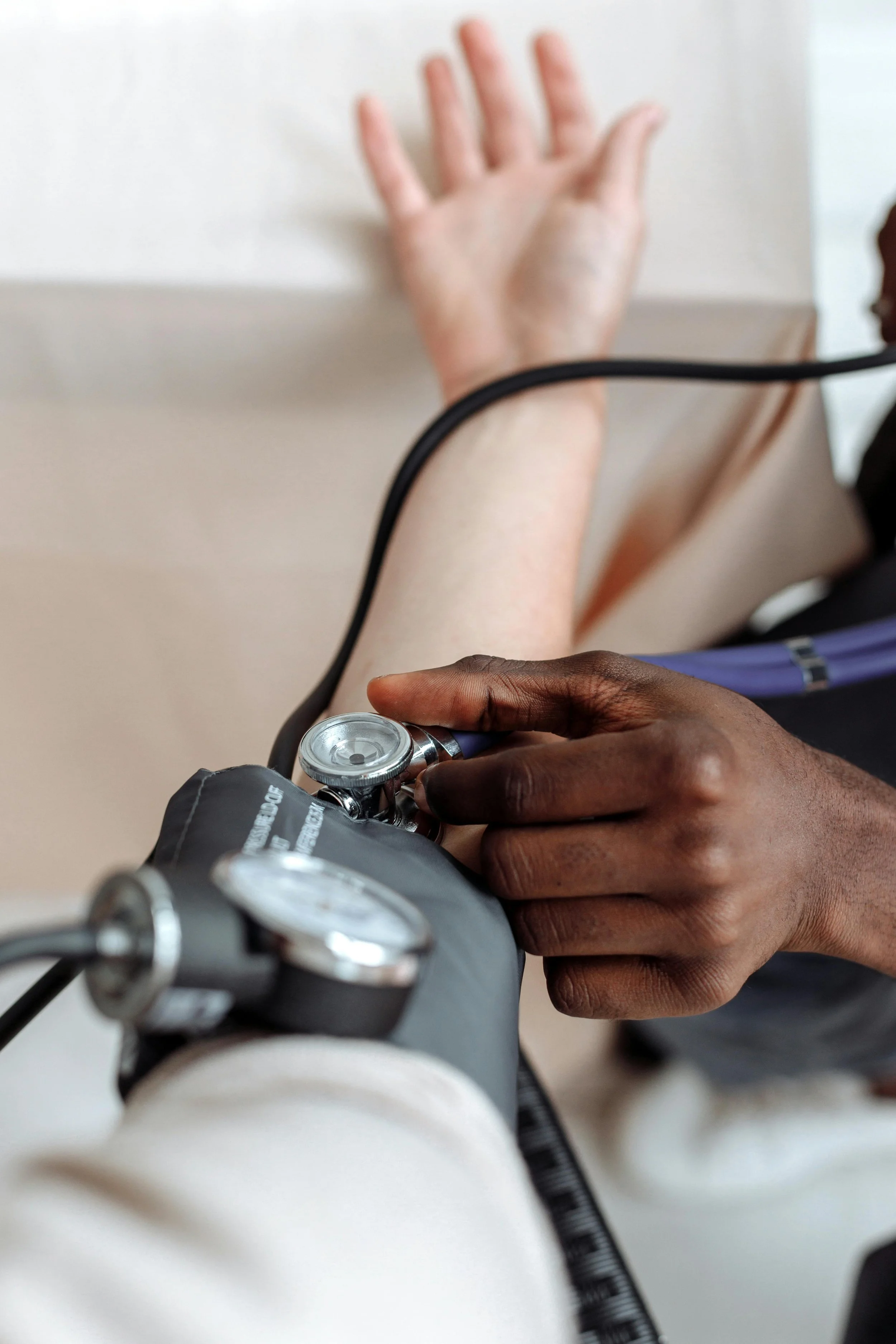 Checking blood pressure with a stethoscope underneath a blood pressure cuff. 