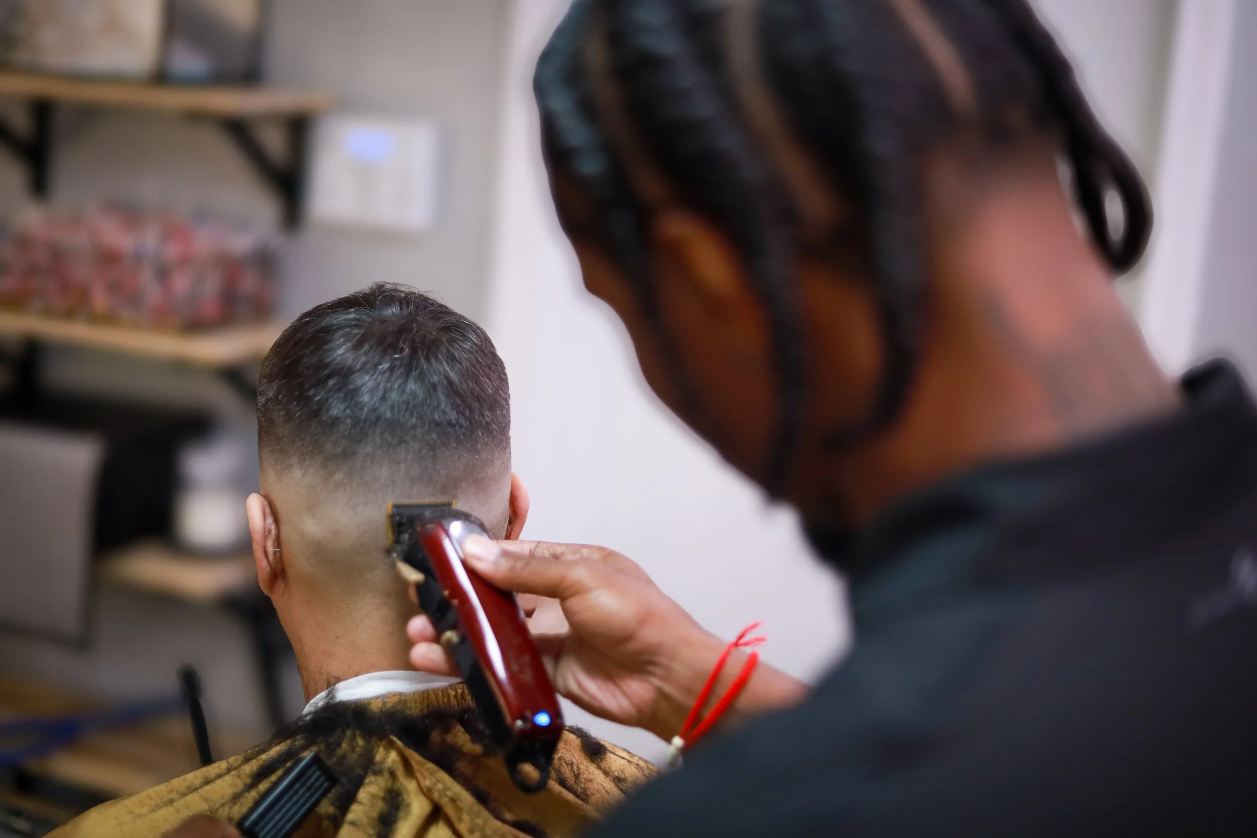 Barber using clippers to trim a man's hair at a barbershop.