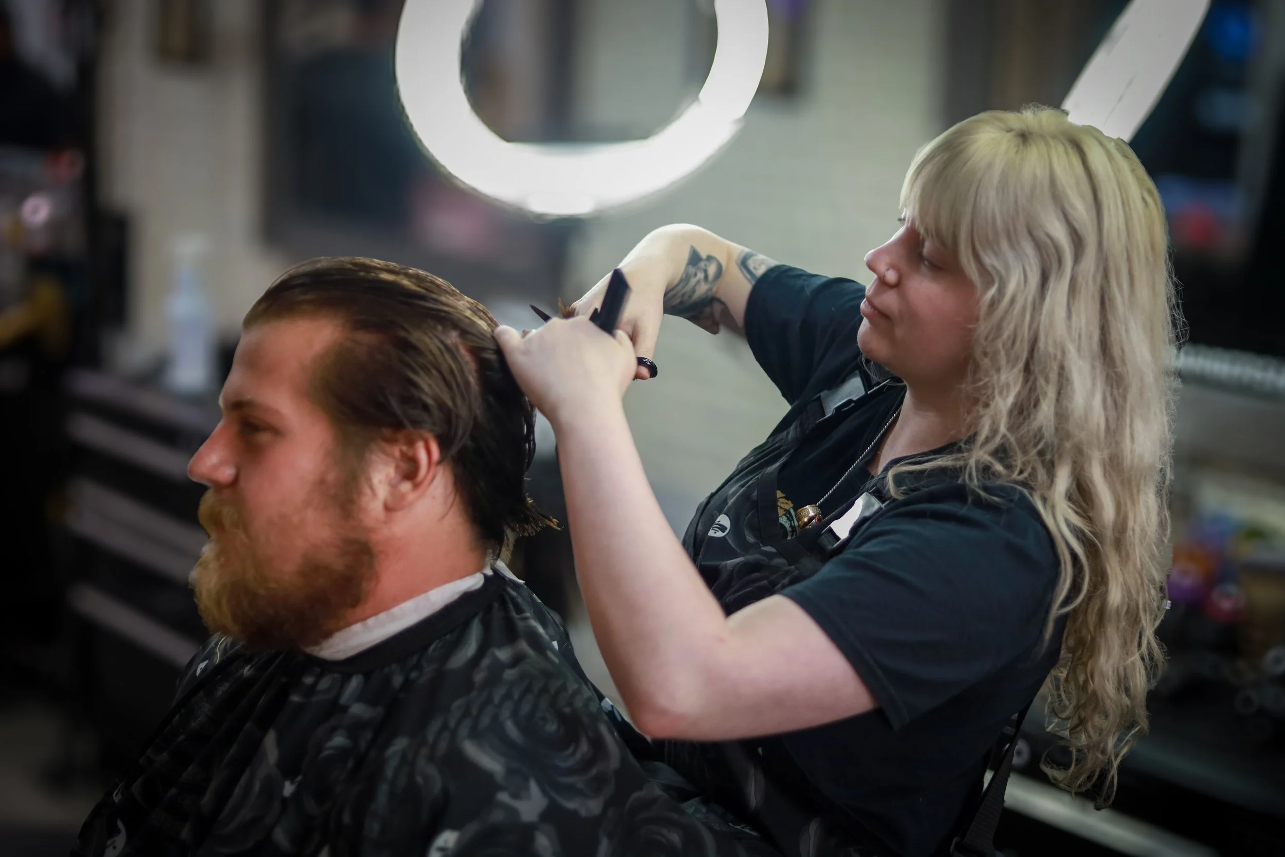 A hairstylist cutting a man's hair in a salon.
