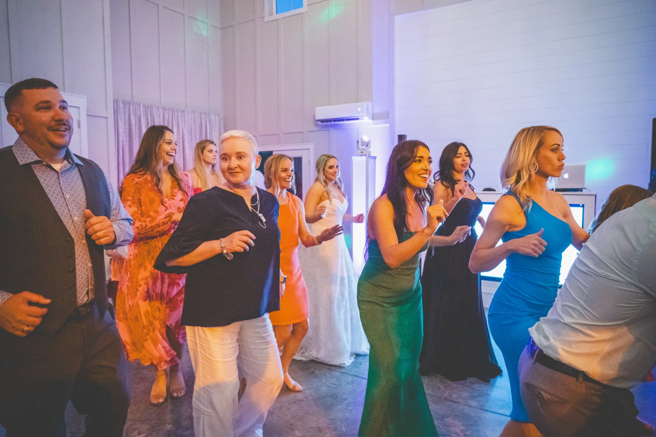 People dancing and having fun at a party or celebration in a decorated room with colorful lights.