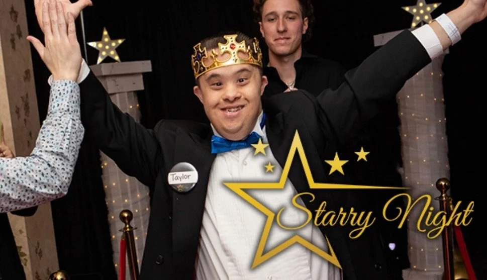 A young man in formal attire wearing a crown and a blue bowtie, smiling with arms raised, celebrating at an event called 'Starry Night' with a background decorated with stars and lights.