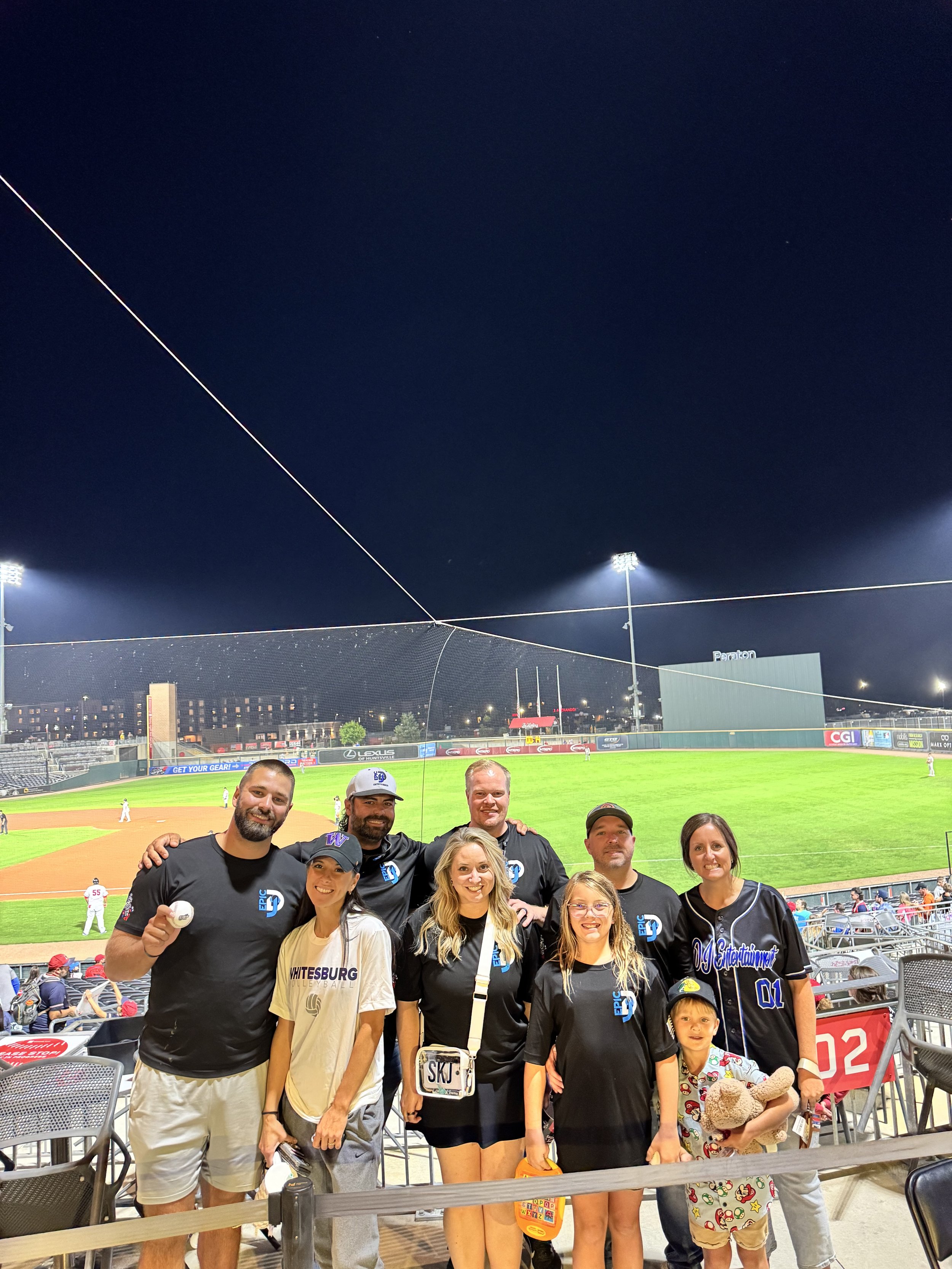 Group of people at a baseball game posing for a photo.