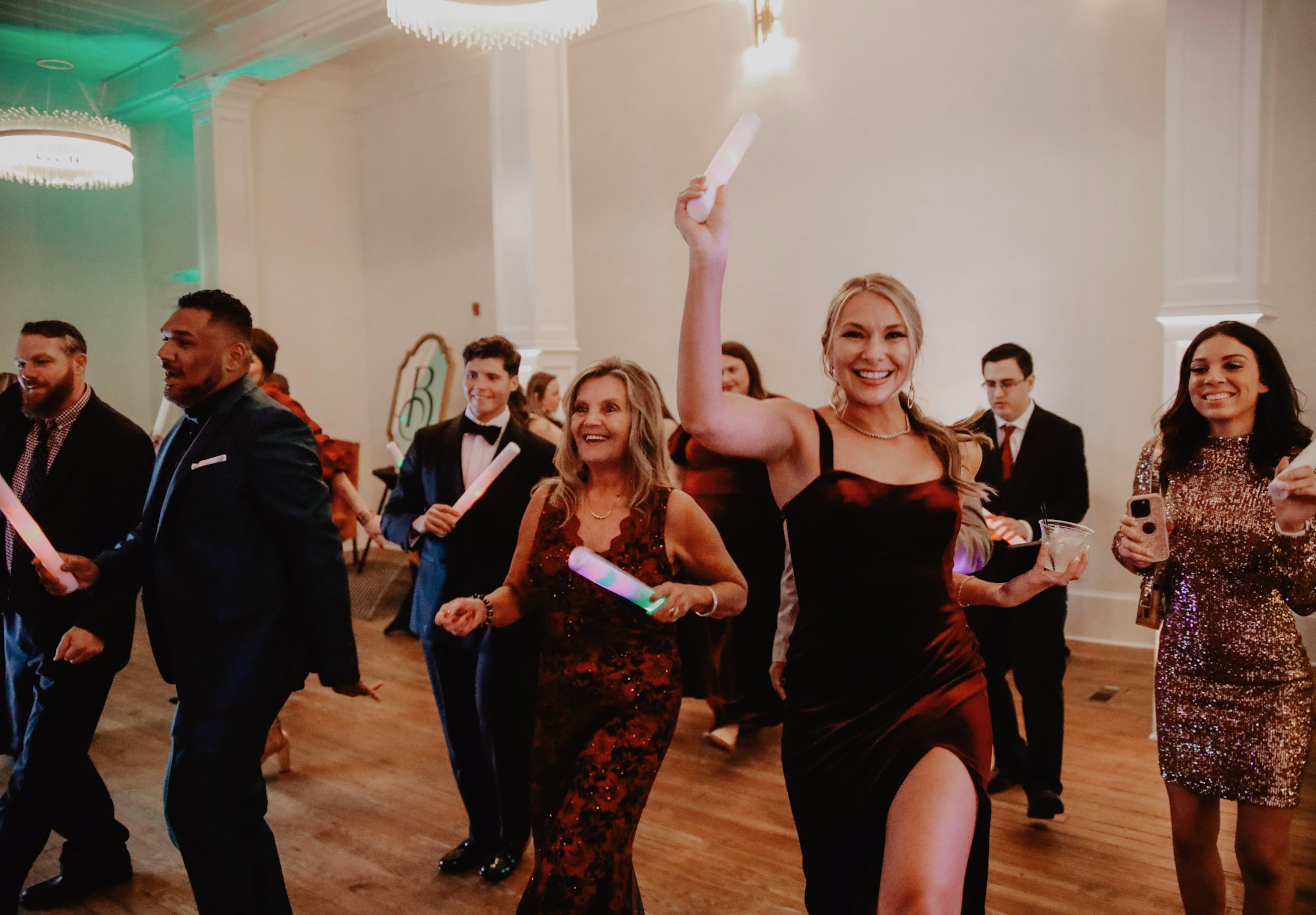 People dancing and celebrating at a formal event or party in a decorated hall, with elegant attire and joyful expressions.