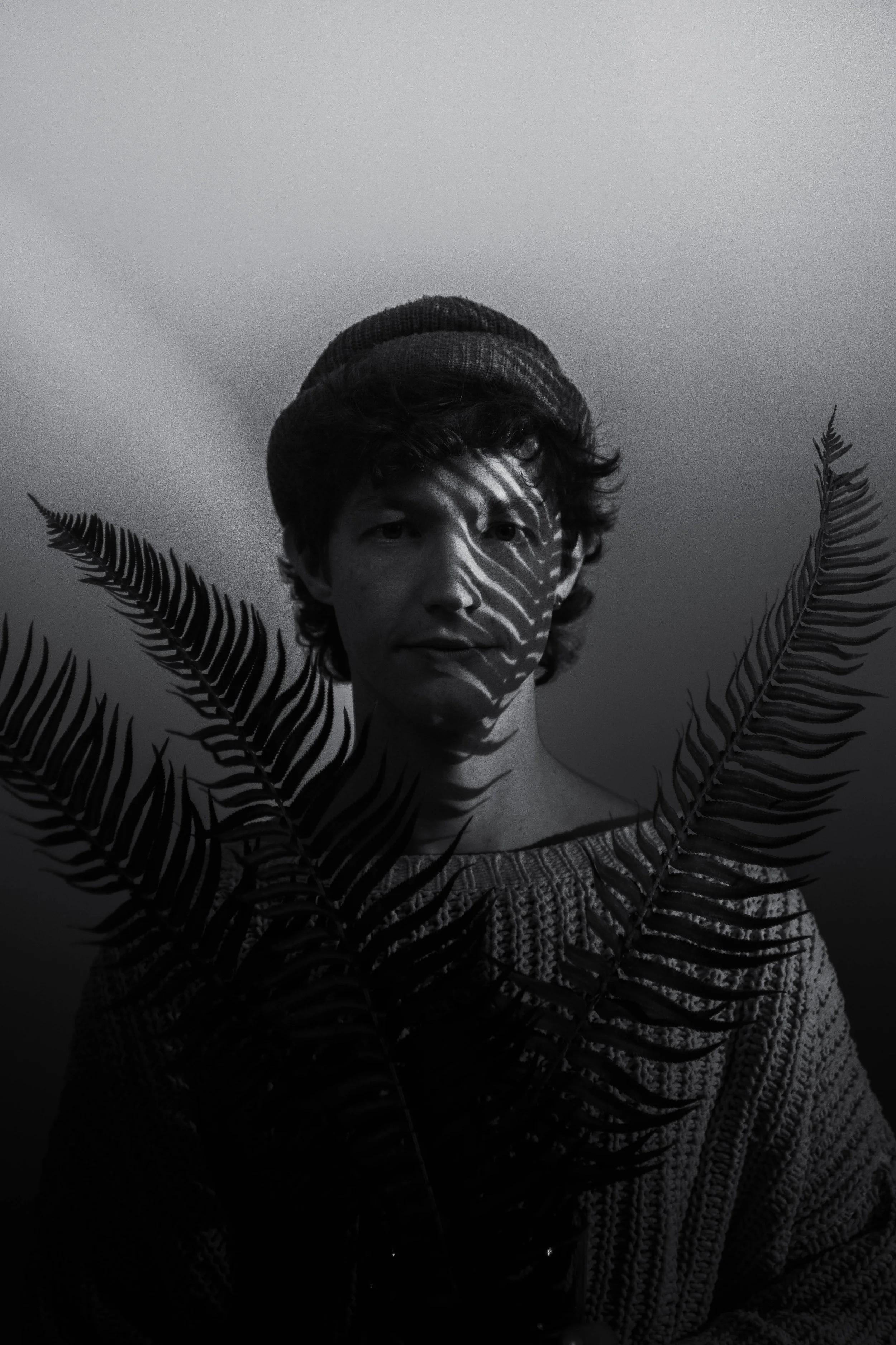 Creative black and white portrait in studio using plants as shadows. Part of Catlyn Sue’s portrait photography sessions, showcasing artistic style in shadows and shapes in studio settings.