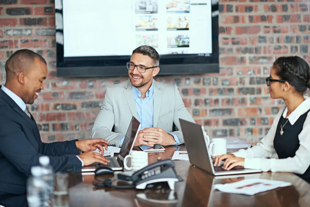 Business professionals collaborating at a conference table with laptops.