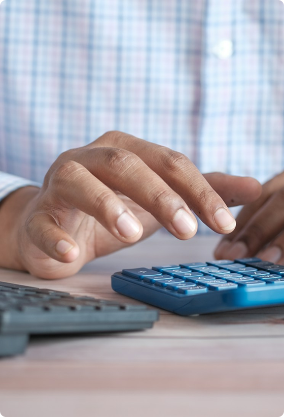 A person using a calculator and a computer keyboard.