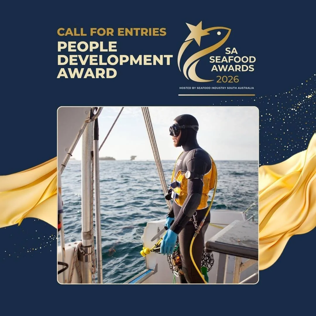 A man with a robotic arm gazing out over the ocean on a boat, wearing scuba diving gear and a yellow life vest, with the sea and distant ships in the background.