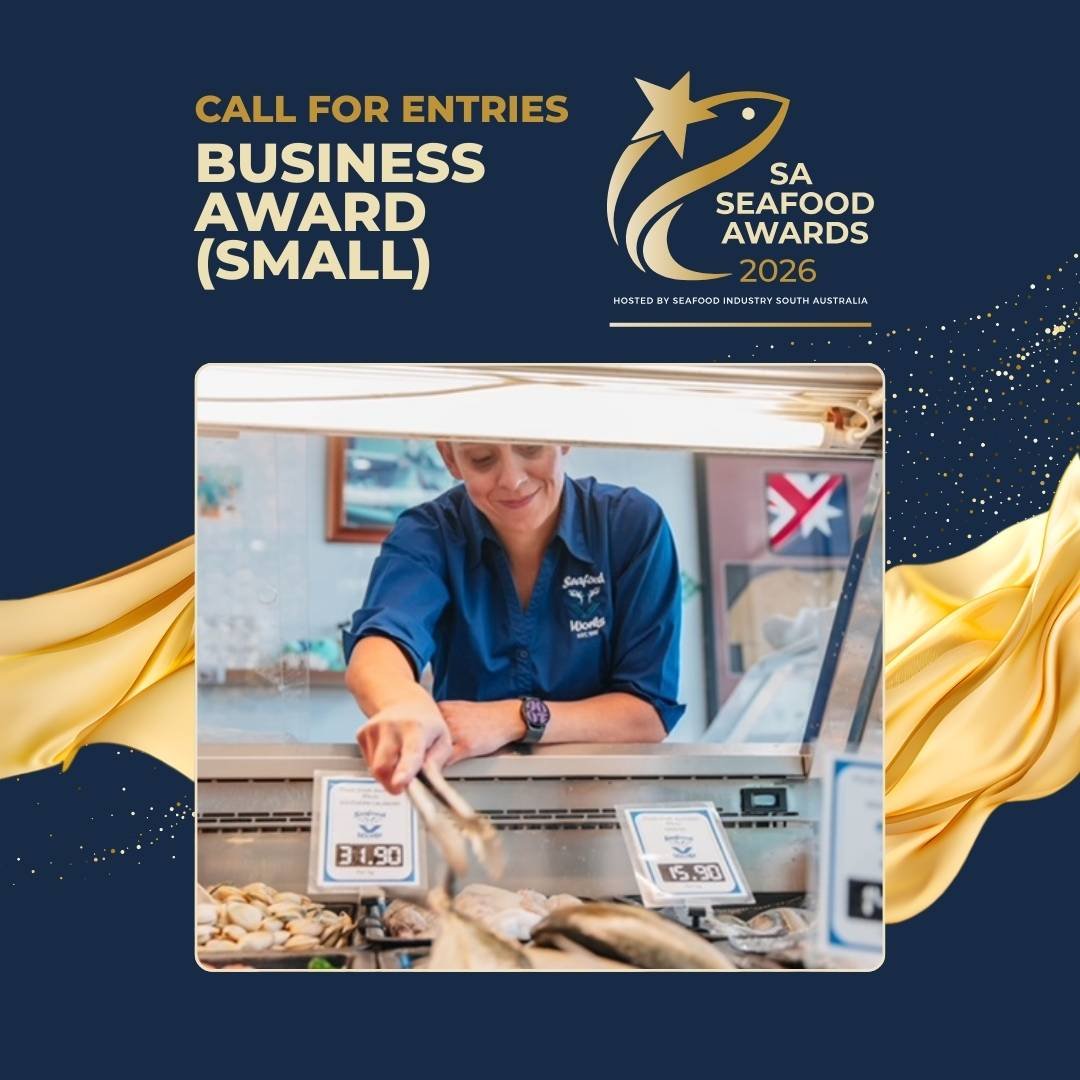 A woman wearing a blue shirt is selecting seafood from a display case at a seafood market. The display includes prices for different types of fish.